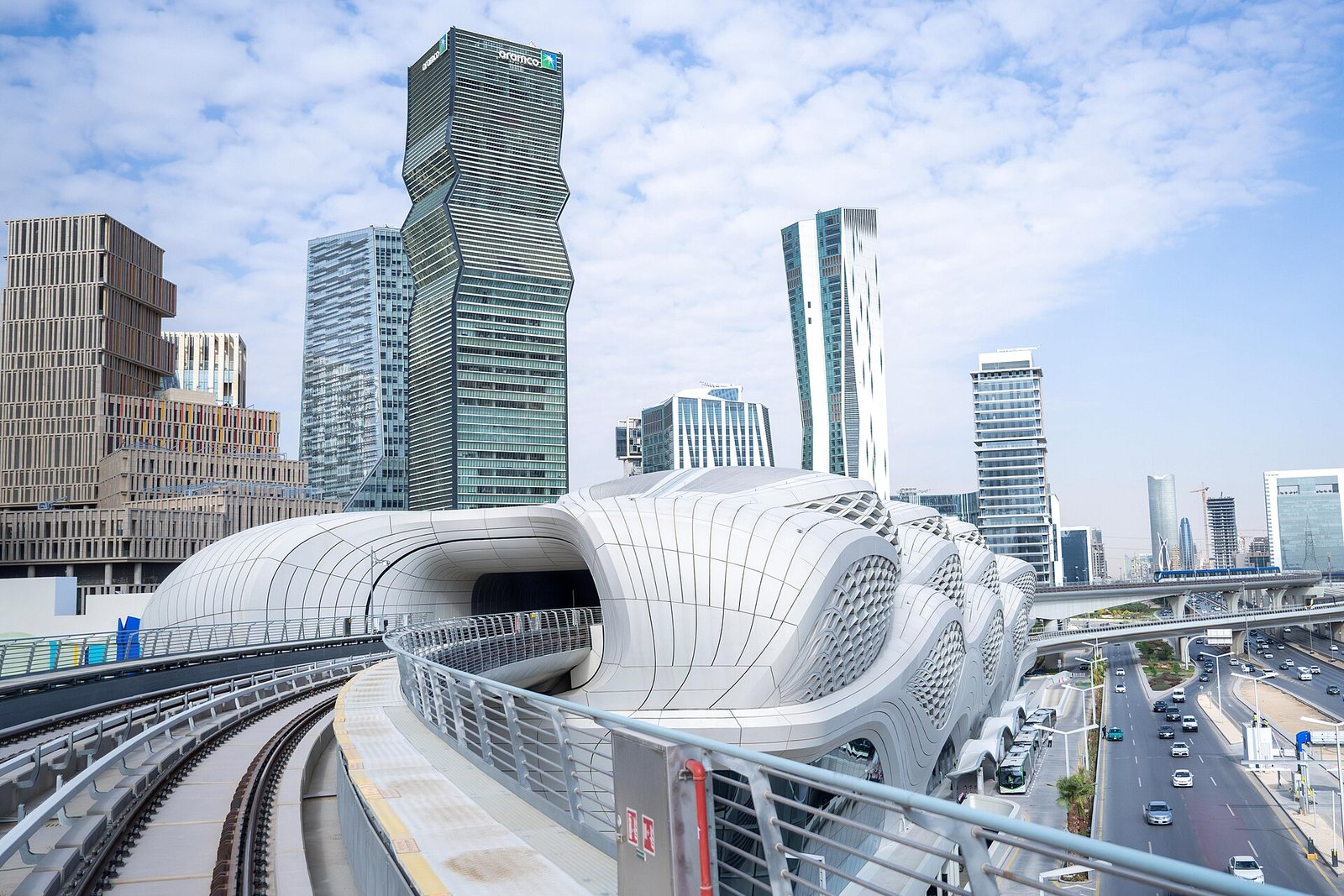 The sculpted, wave-like Riyadh Metro station at King Abdullah Financial District, framed by the district's towers.