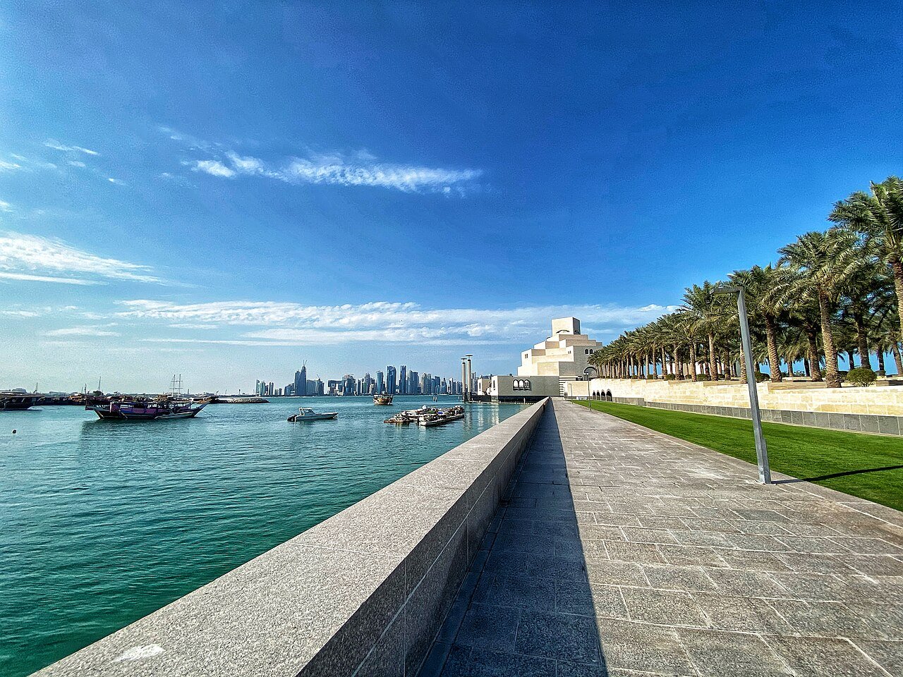 The Museum of Islamic Art rising across the turquoise water of Doha Bay, with the West Bay towers on the horizon.