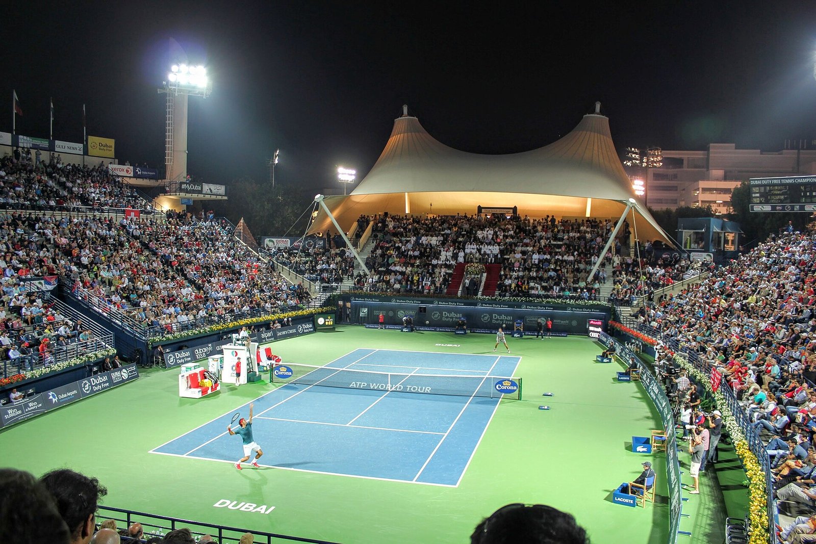 A floodlit night semi-final at the Dubai Duty Free Tennis Stadium, its tented stand glowing above the blue court.