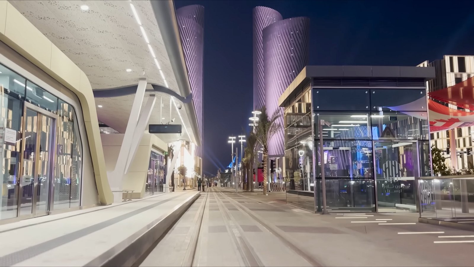 The Lusail Plaza Towers glowing above the shops and promenade of Lusail Boulevard at night.