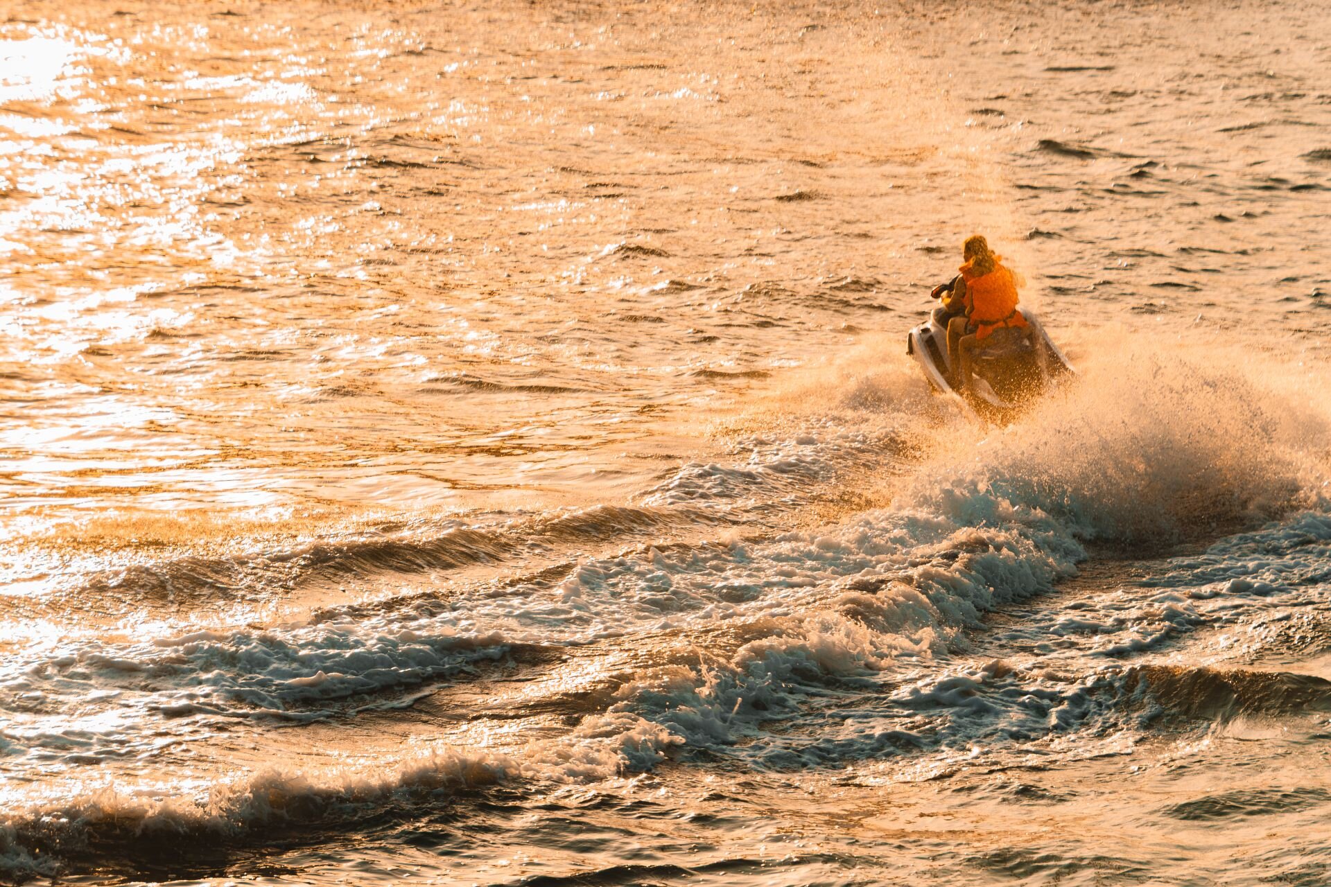 A jet ski cutting through golden water at sunset