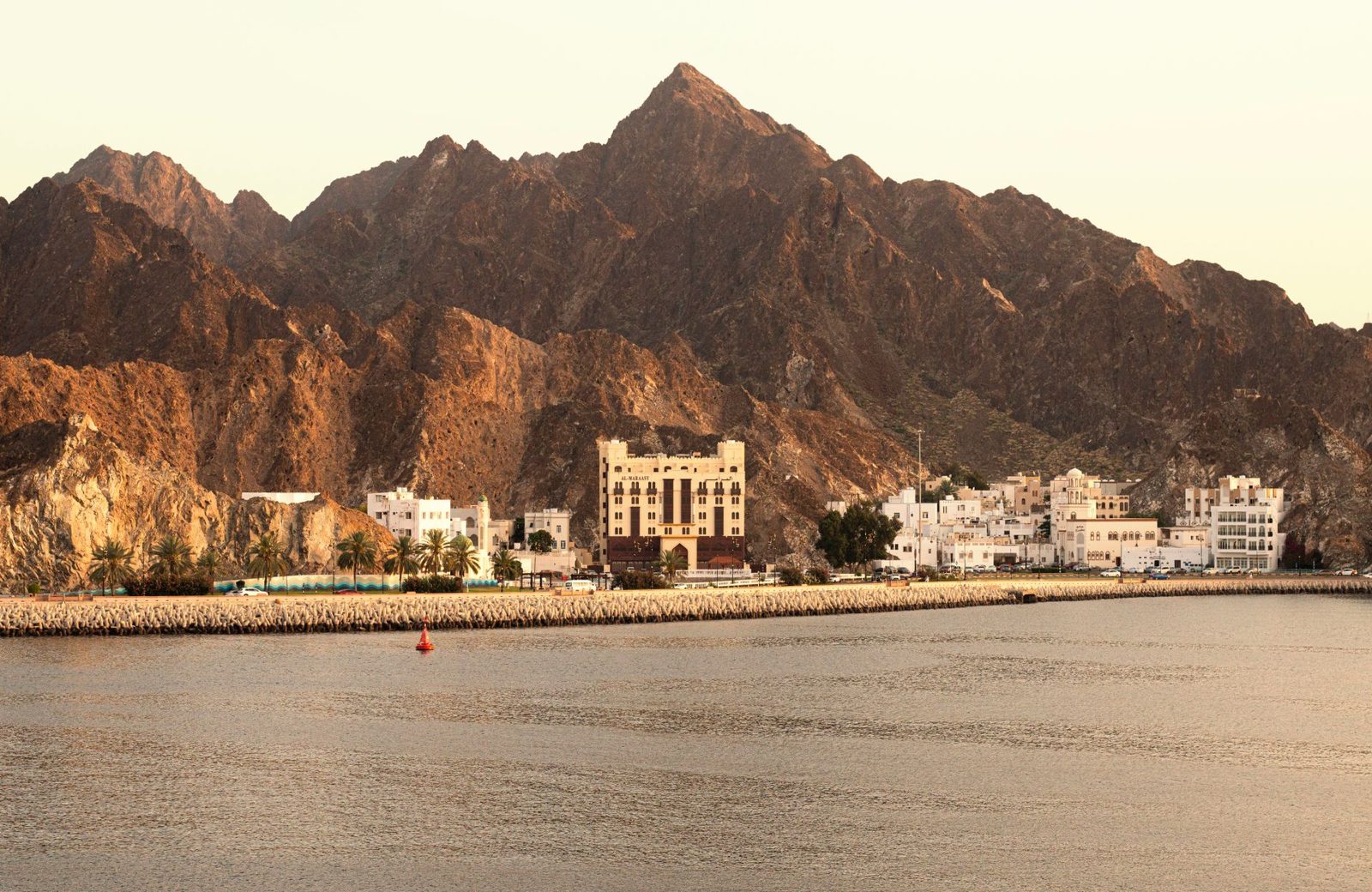 The corniche road curving around the bay below the mountains of Muscat