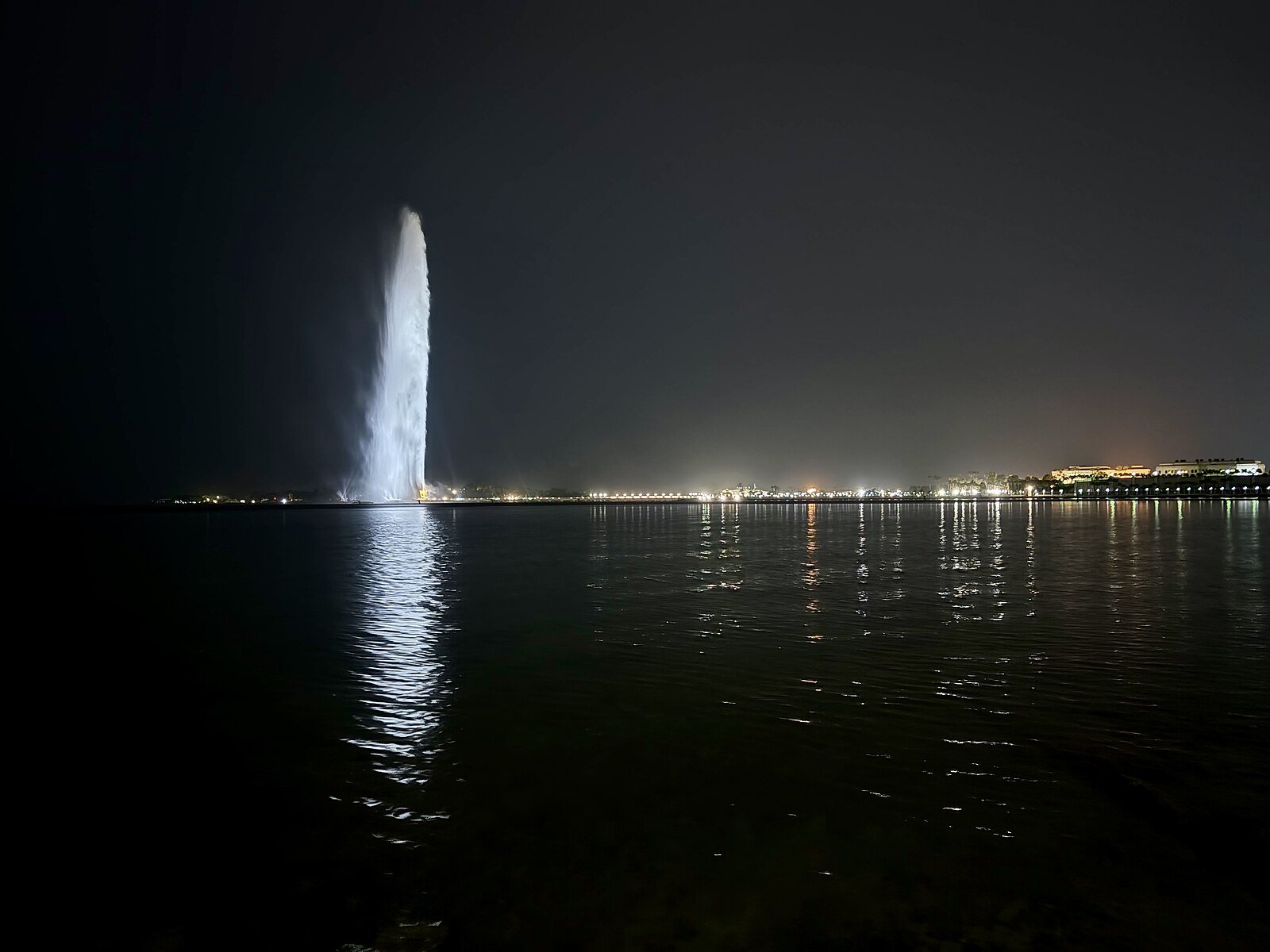 King Fahd's Fountain soaring above the Red Sea at night, its plume mirrored in the water off the Jeddah Corniche.