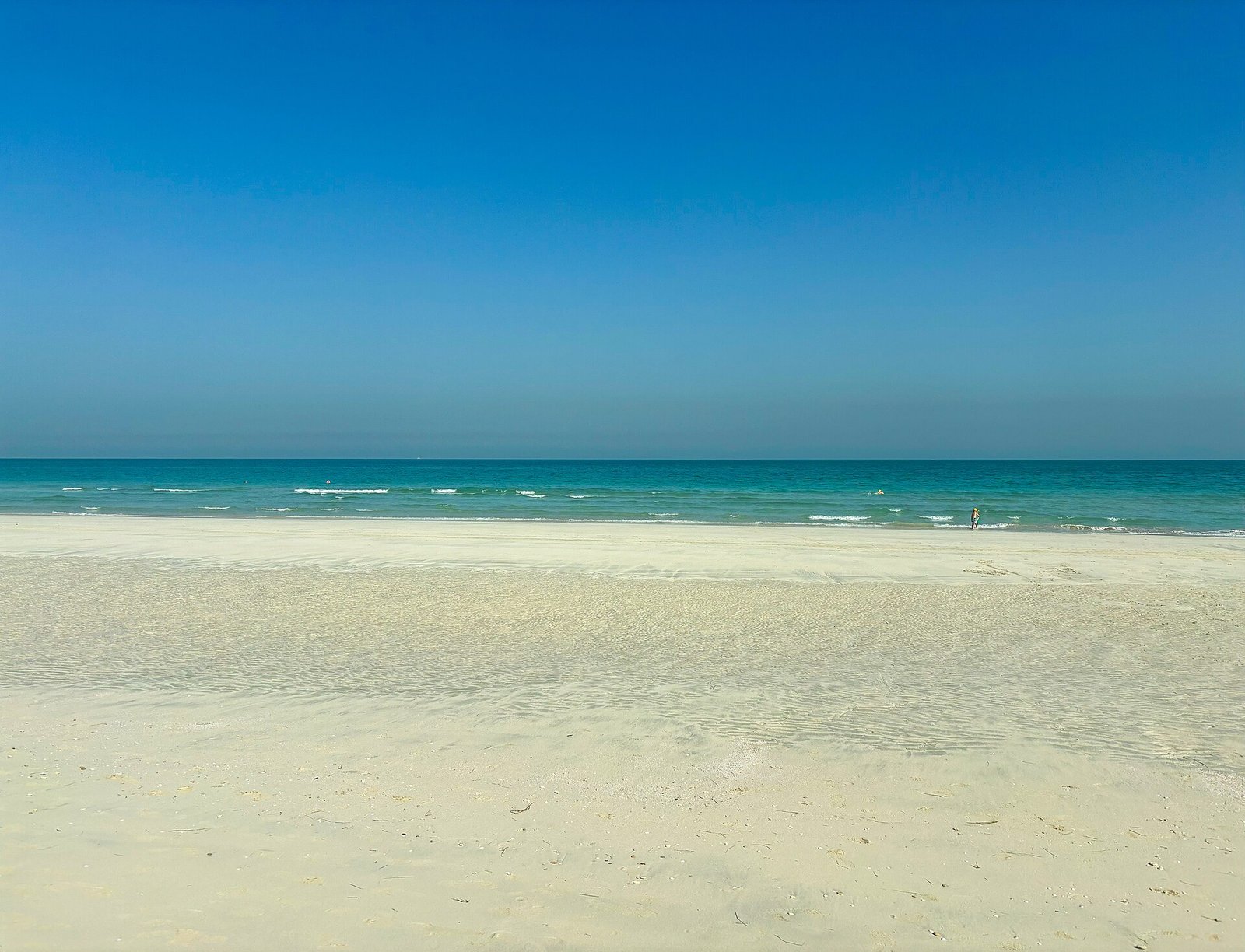 A quiet morning on Saadiyat Island's broad white beach, with clear turquoise shallows