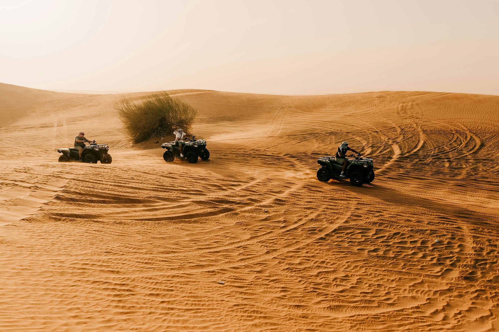 Quad bikes curving across the red sand