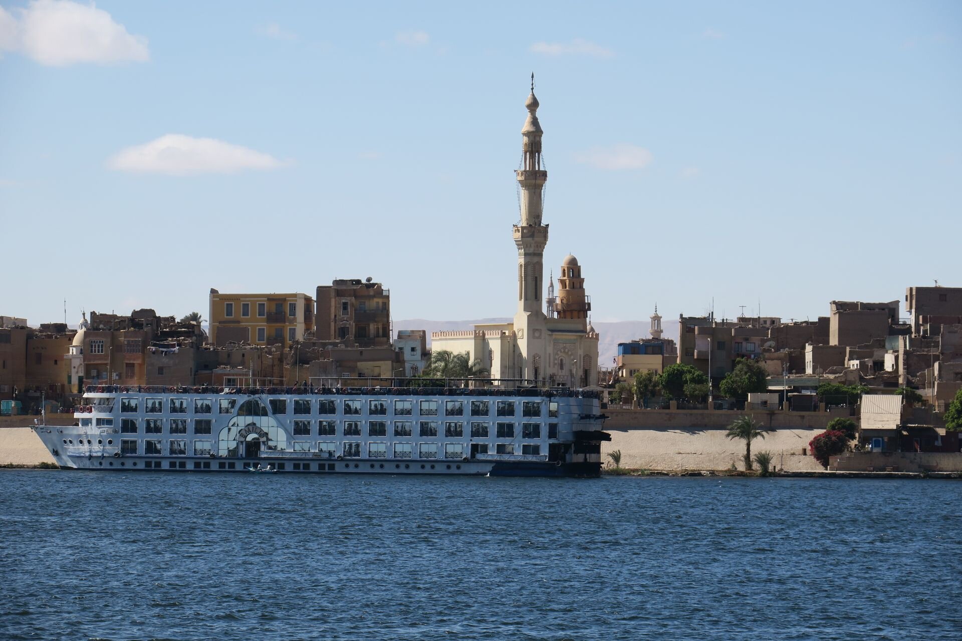 A Nile cruise ship moored below a mosque on the riverbank, Egypt