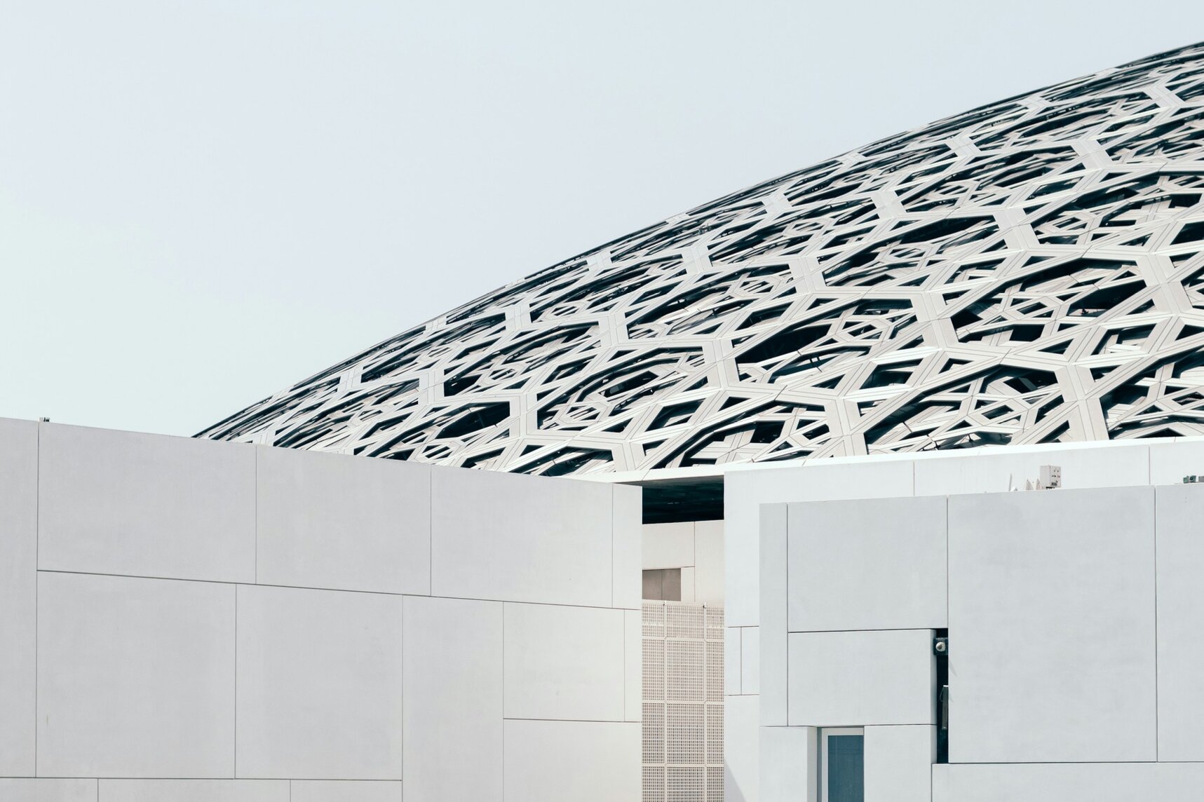 The latticed dome of the Louvre Abu Dhabi above white galleries and the sea, Saadiyat Island