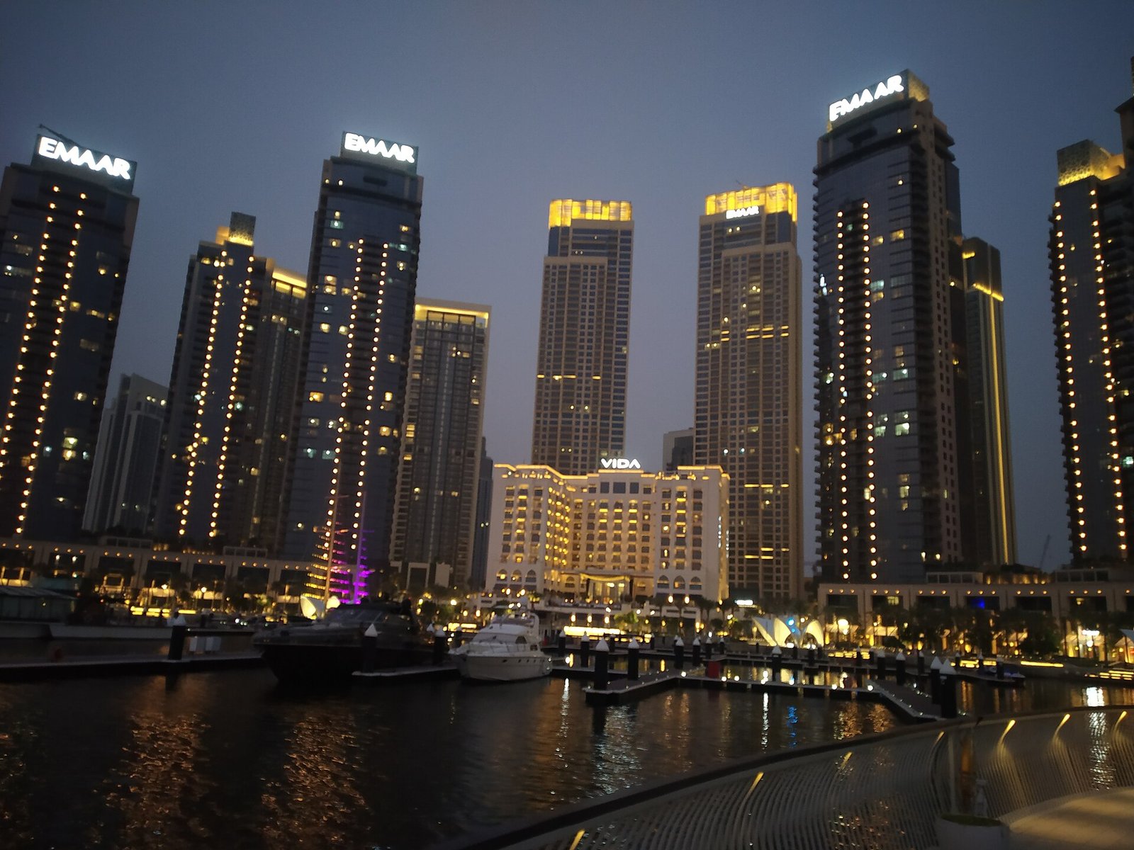 The towers of Dubai Creek Harbour lit at dusk above the marina