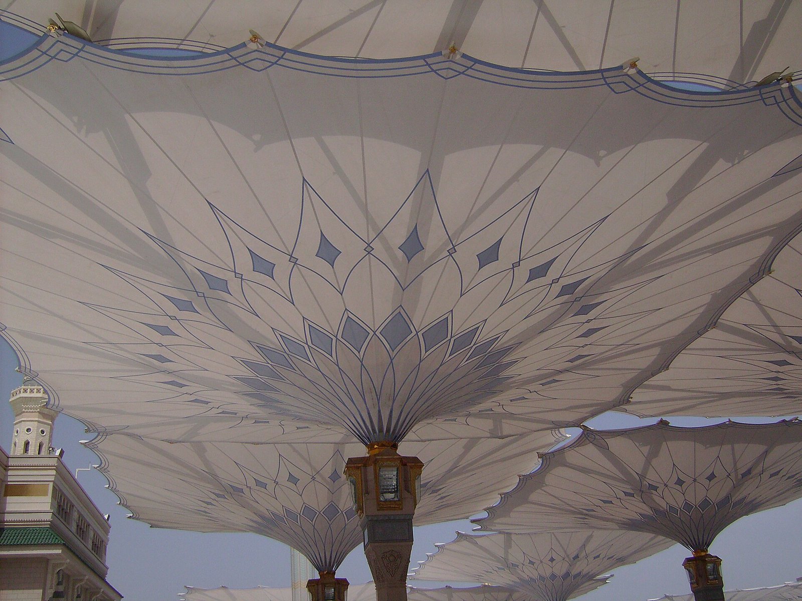 The great retractable sunshade umbrellas over the plaza of the Prophet's Mosque in Madinah, with a minaret beyond.