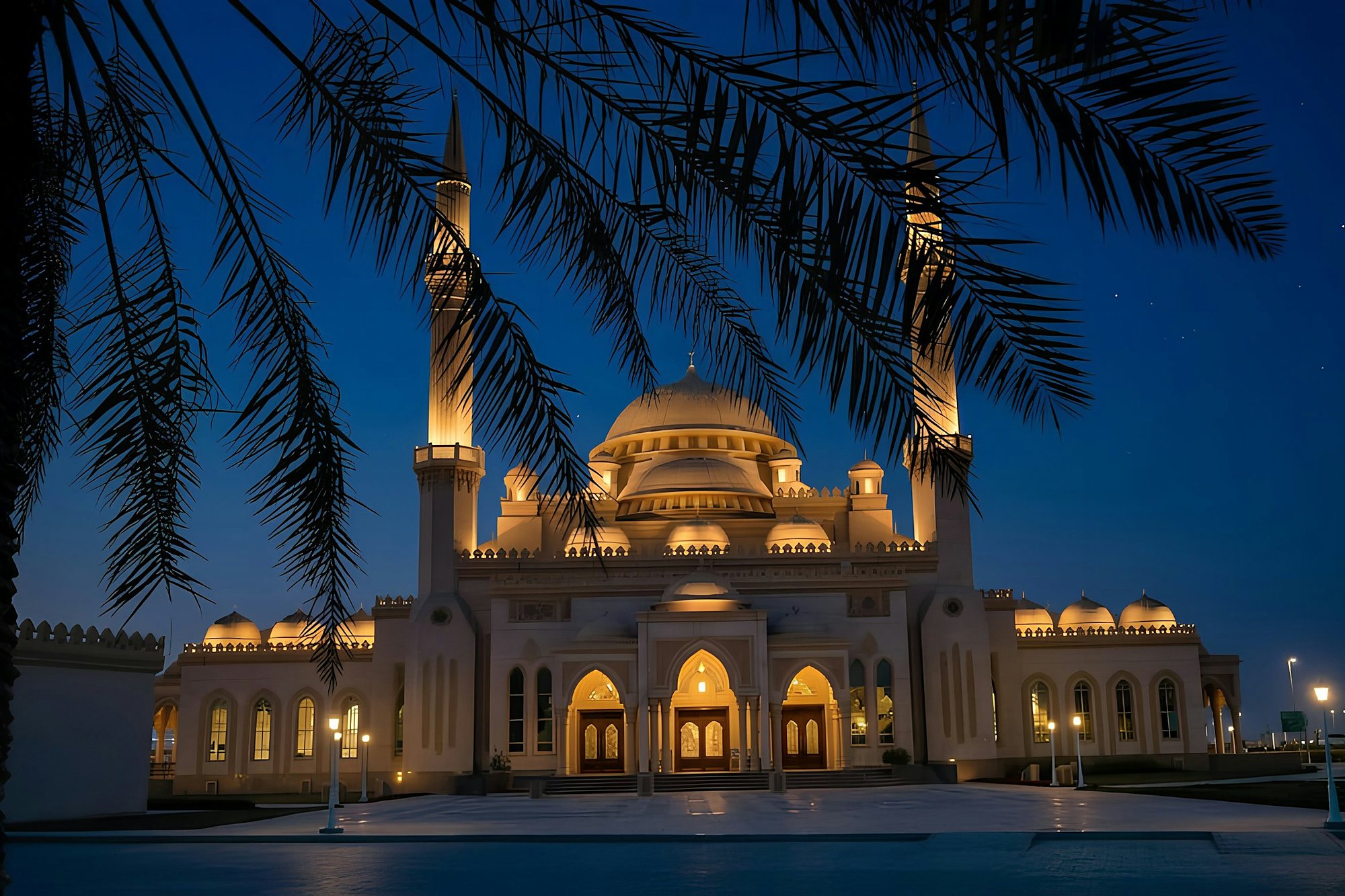 A mosque lit gold at night, framed by palm fronds
