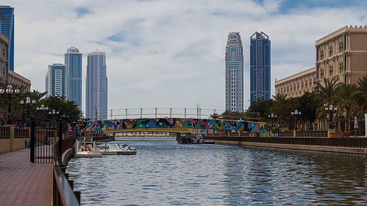 The Al Qasba canal in Sharjah, lined with palms and promenades beneath the city's towers.