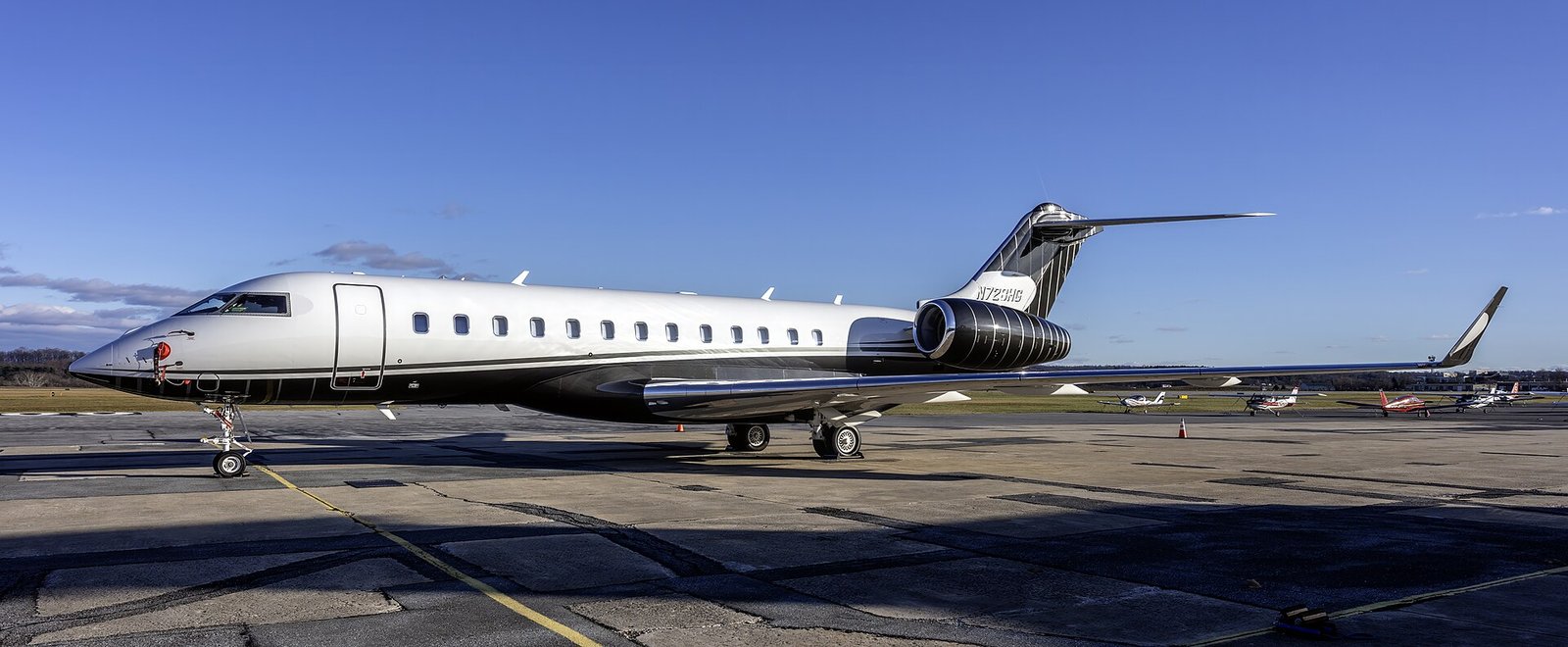 A Bombardier Global 6000 business jet parked on a private aviation apron beneath an open sky.