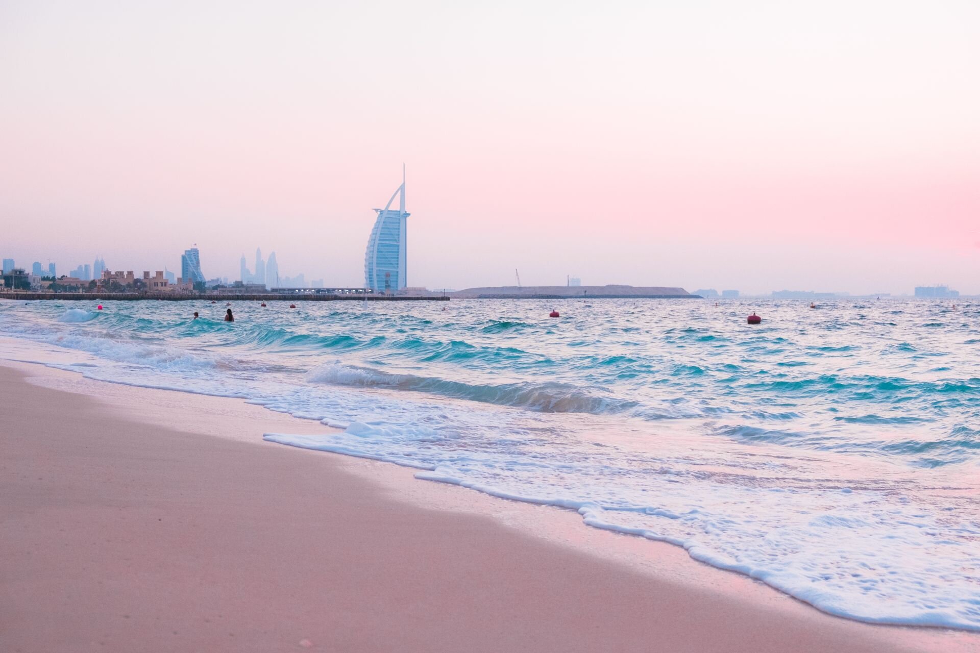 The Burj Al Arab beyond the waves of Jumeirah Beach at a pink dusk, Dubai