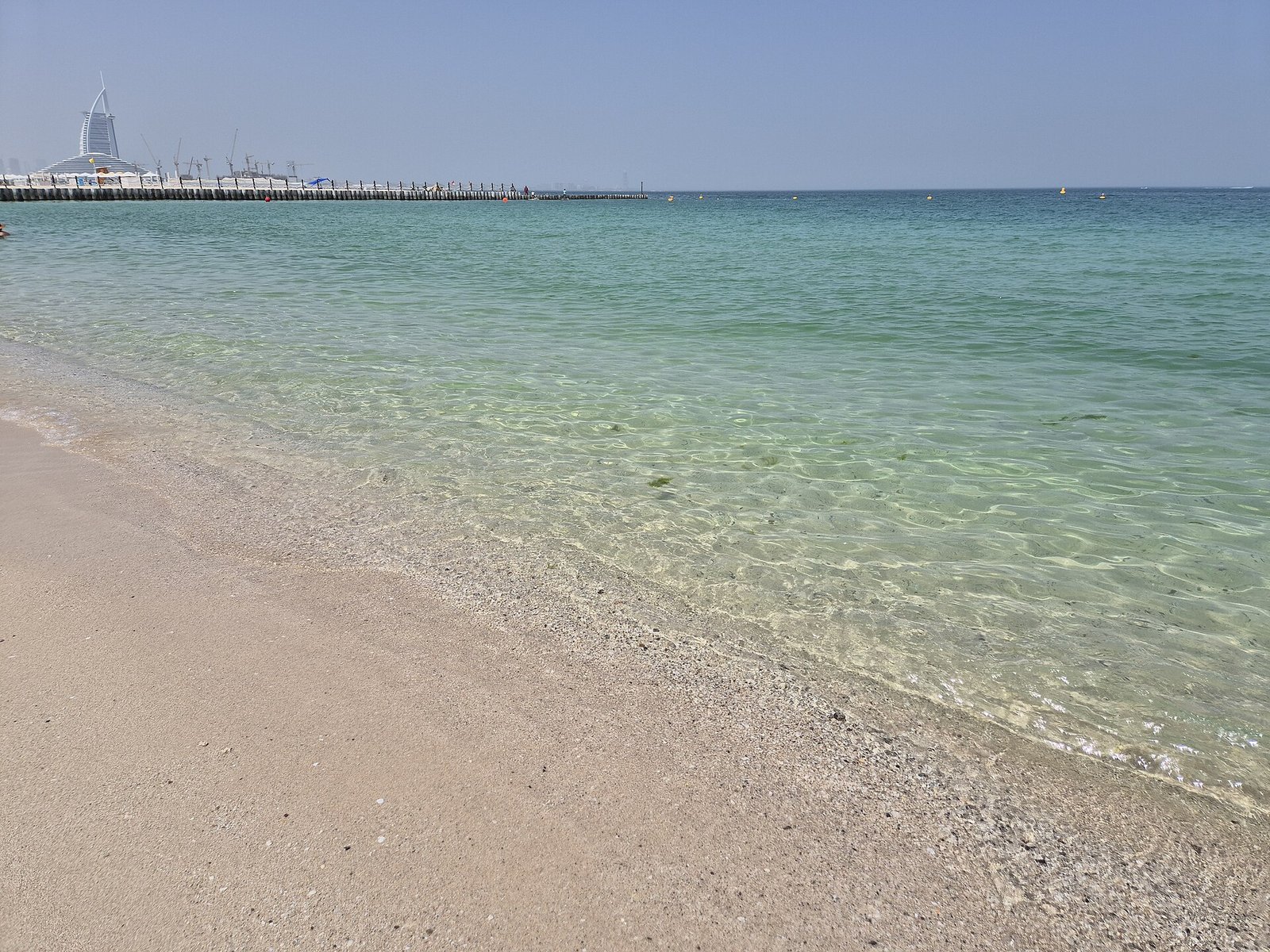 Clear turquoise shallows along Kite Beach in Dubai, with the Burj Al Arab on the horizon