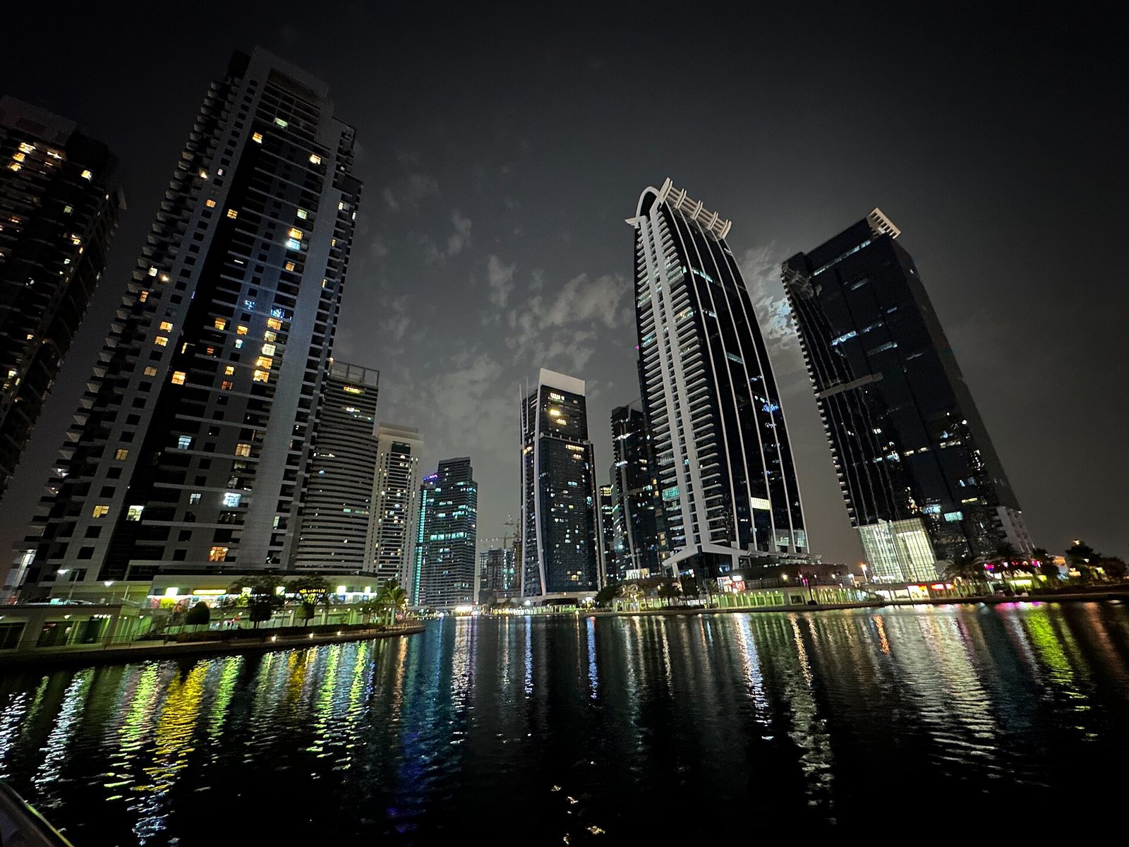 The towers of Jumeirah Lakes Towers, home of the DMCC free zone, reflected in the lake at night, Dubai.