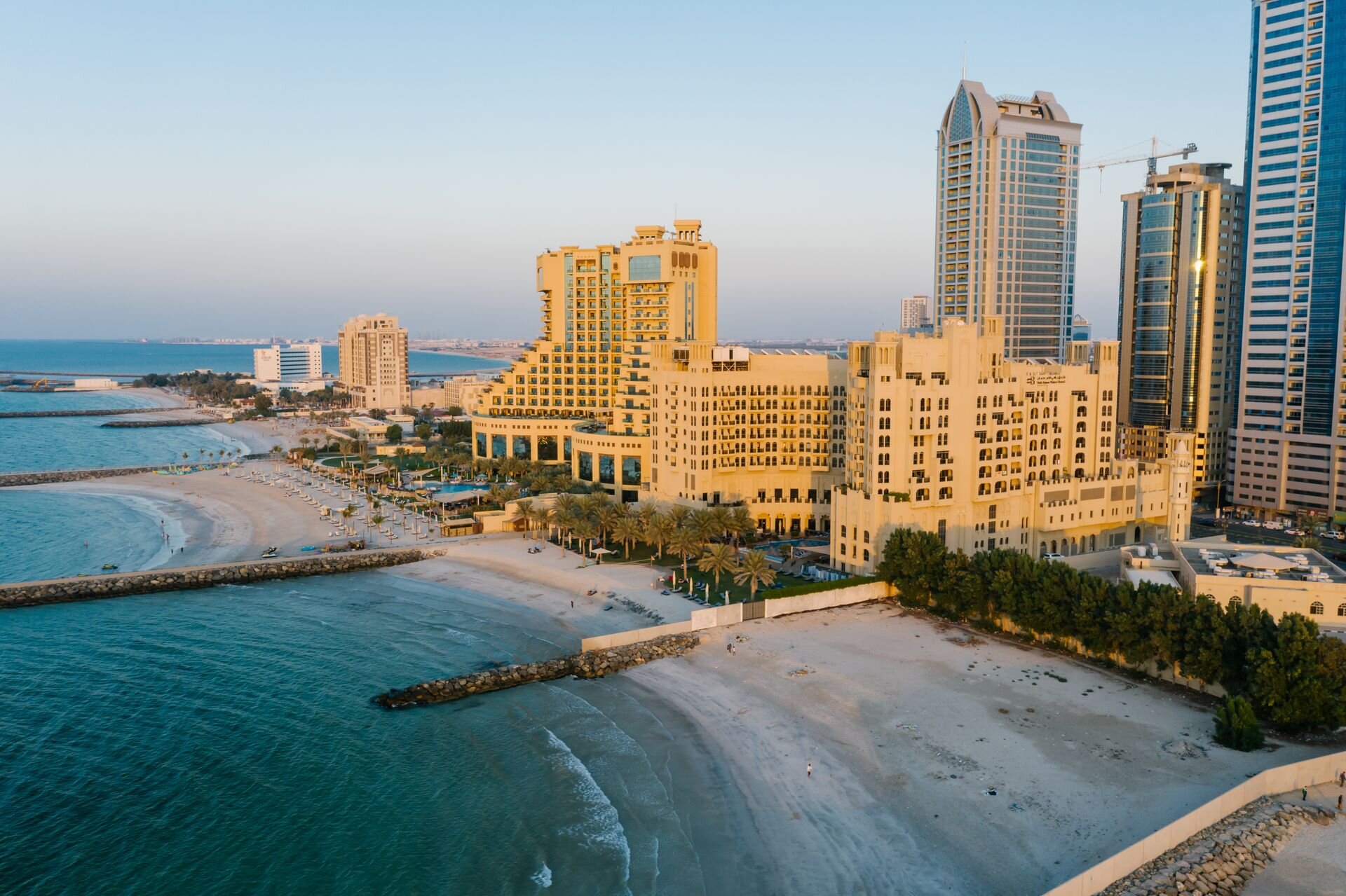 The Ajman Corniche from the air at sunset, with its beachfront hotels and towers