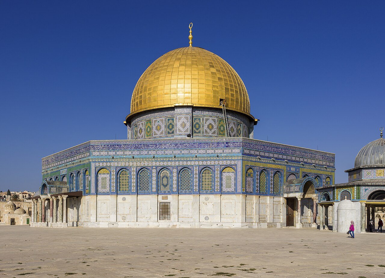 The gilded Dome of the Rock and its blue-tiled octagon on the Temple Mount esplanade in Jerusalem, under a deep blue sky.