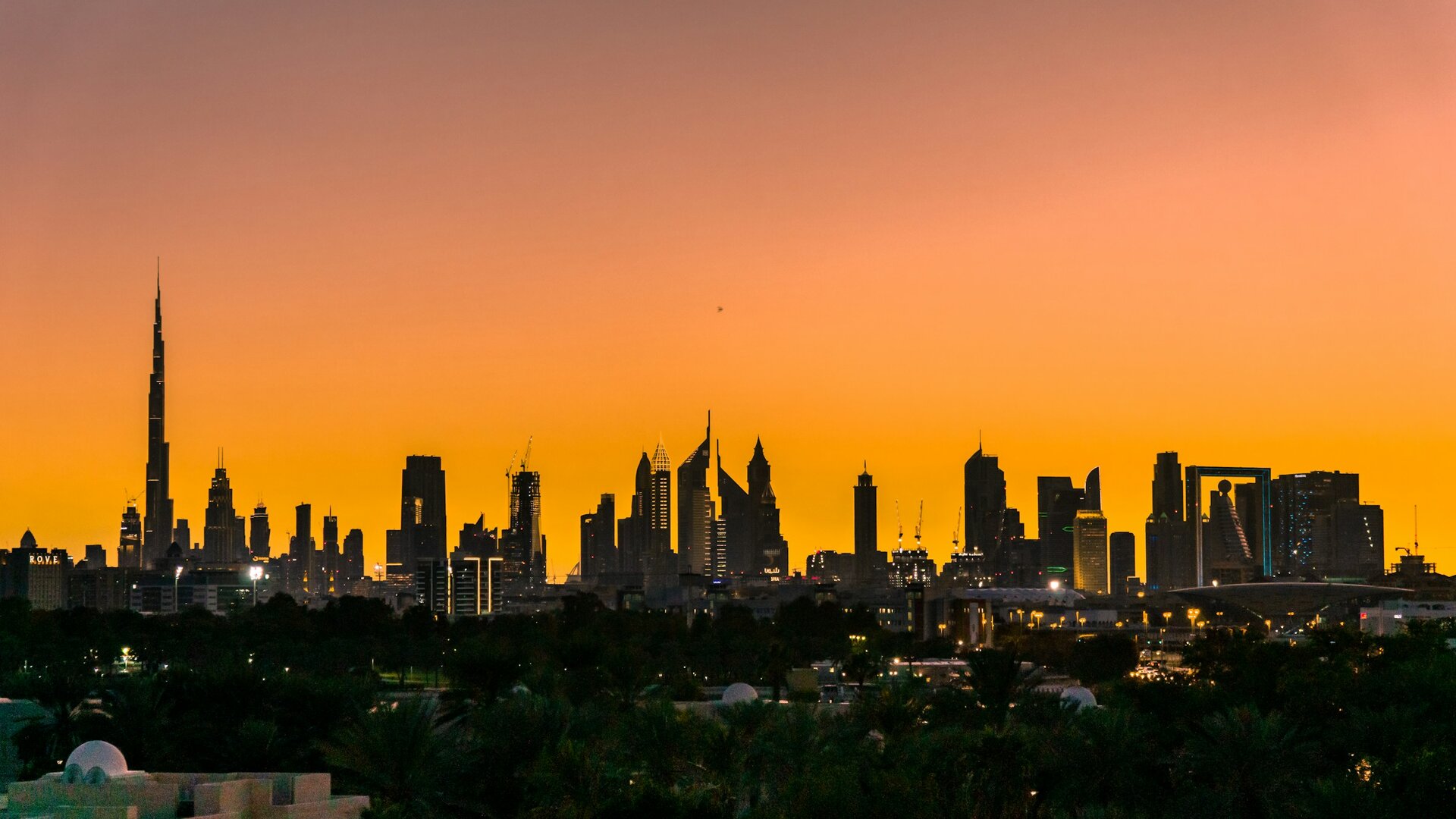 The Burj Khalifa and the Dubai skyline against an orange sunset