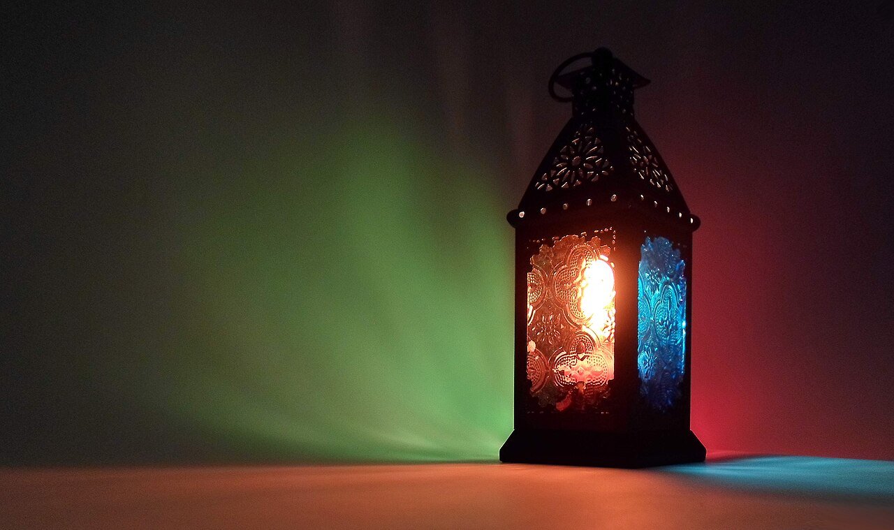 A traditional brass and coloured-glass Ramadan lantern, or fanous, glowing in the dark.