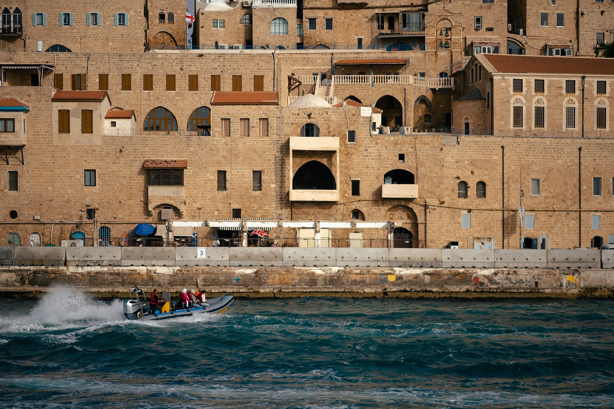 A boat passing the old stone waterfront of Jaffa, Tel Aviv