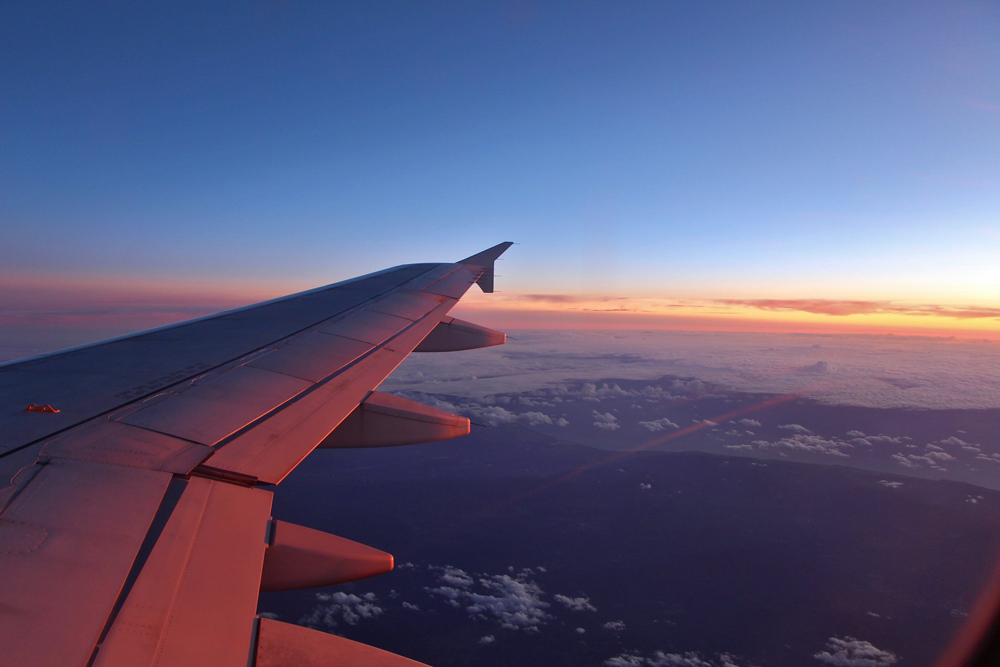 An airliner wing over the clouds at sunset
