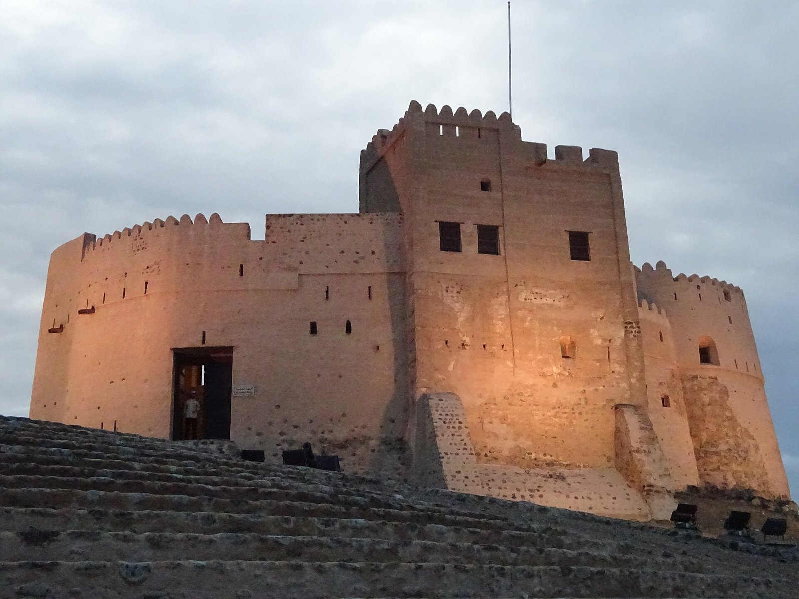 The towers of Fujairah Fort glowing warm in the evening light.