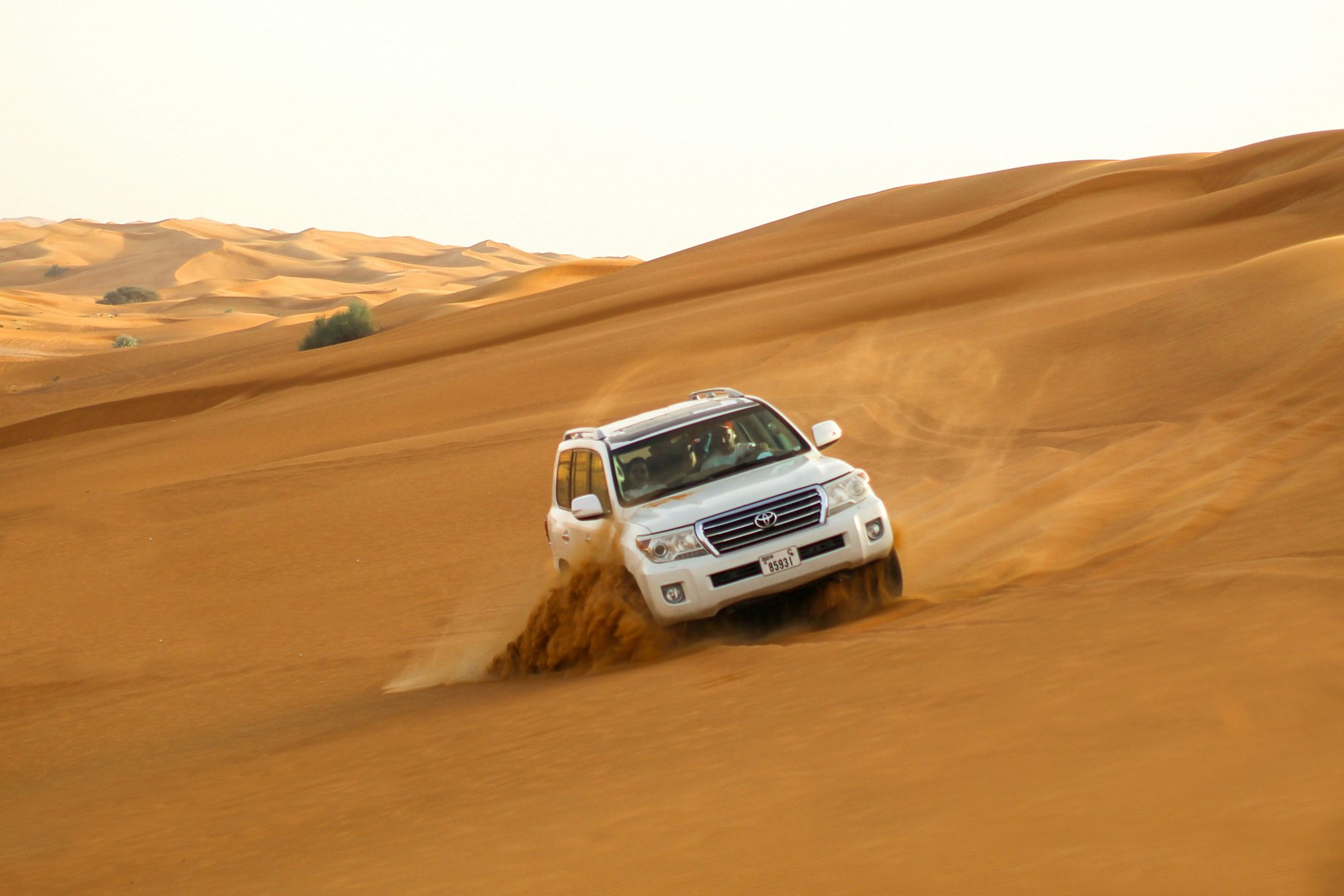 A 4x4 cresting the red dunes on a desert safari