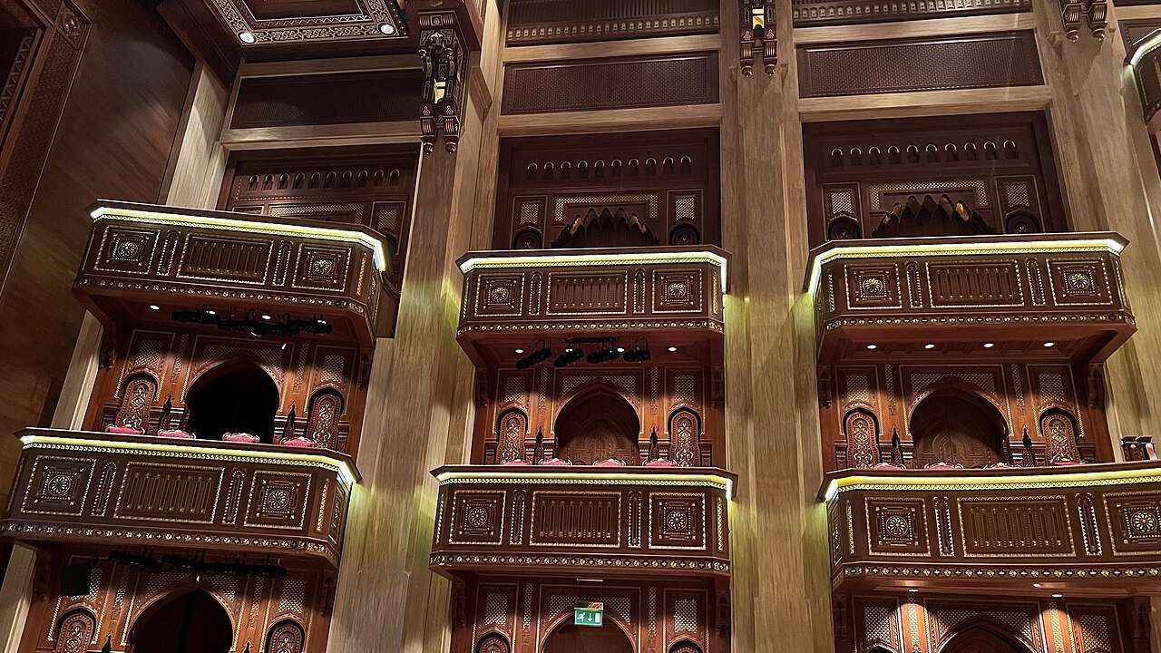 Tiers of carved wooden boxes with gilded detail inside the auditorium of the Royal Opera House Muscat.