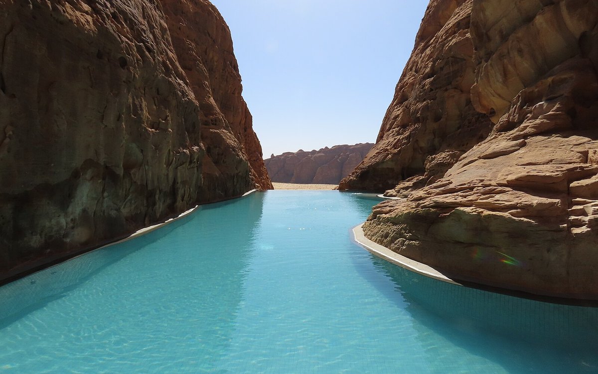 Banyan Tree AlUla's turquoise pool running between the sandstone walls of the Ashar Valley canyon