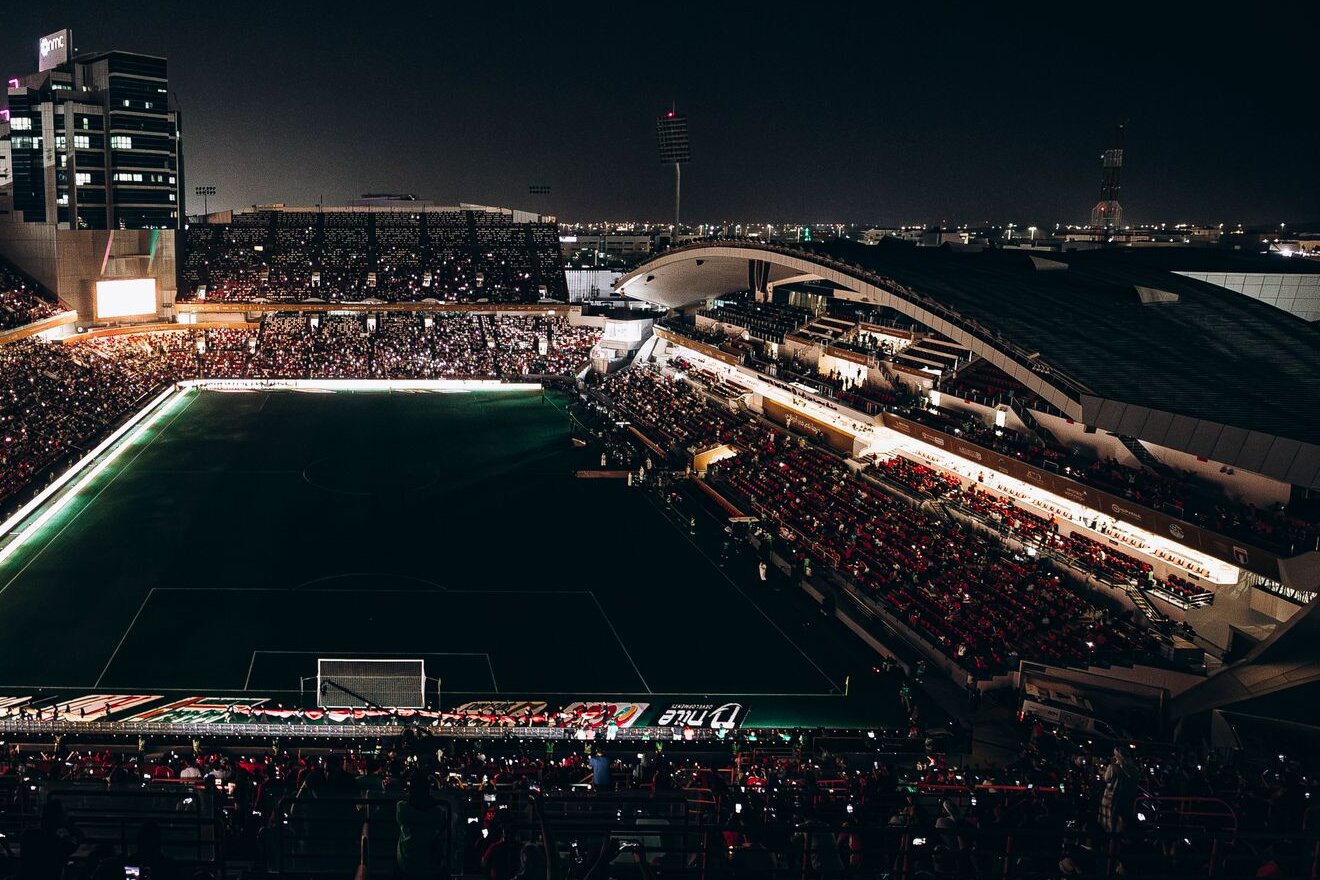 A packed football stadium under floodlights on match night