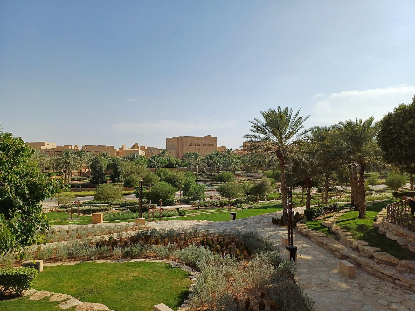 Palm-shaded terraced gardens looking across to the mud-brick walls of At-Turaif, Diriyah.