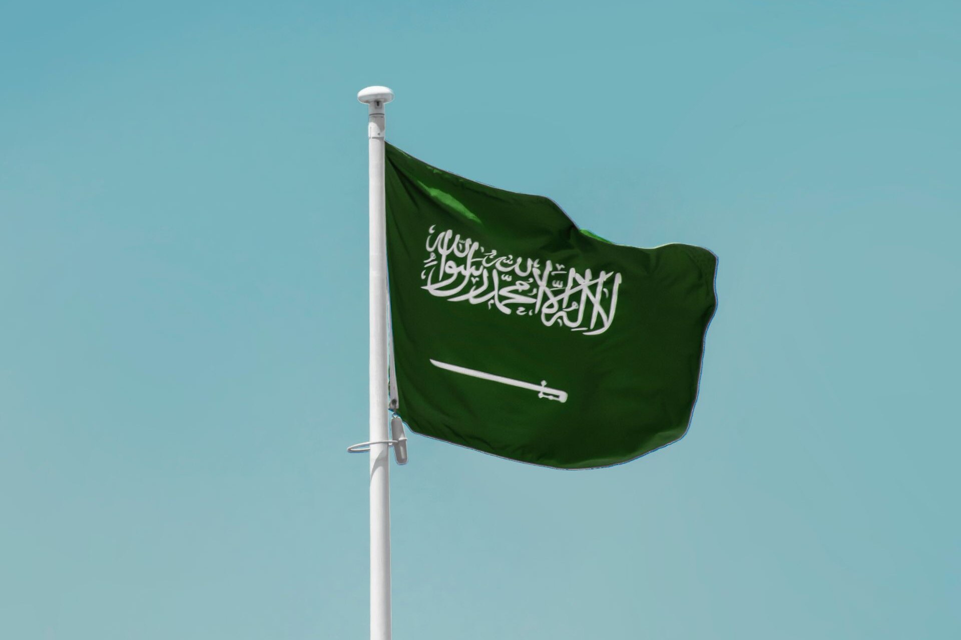 The flag of Saudi Arabia against a clear blue sky