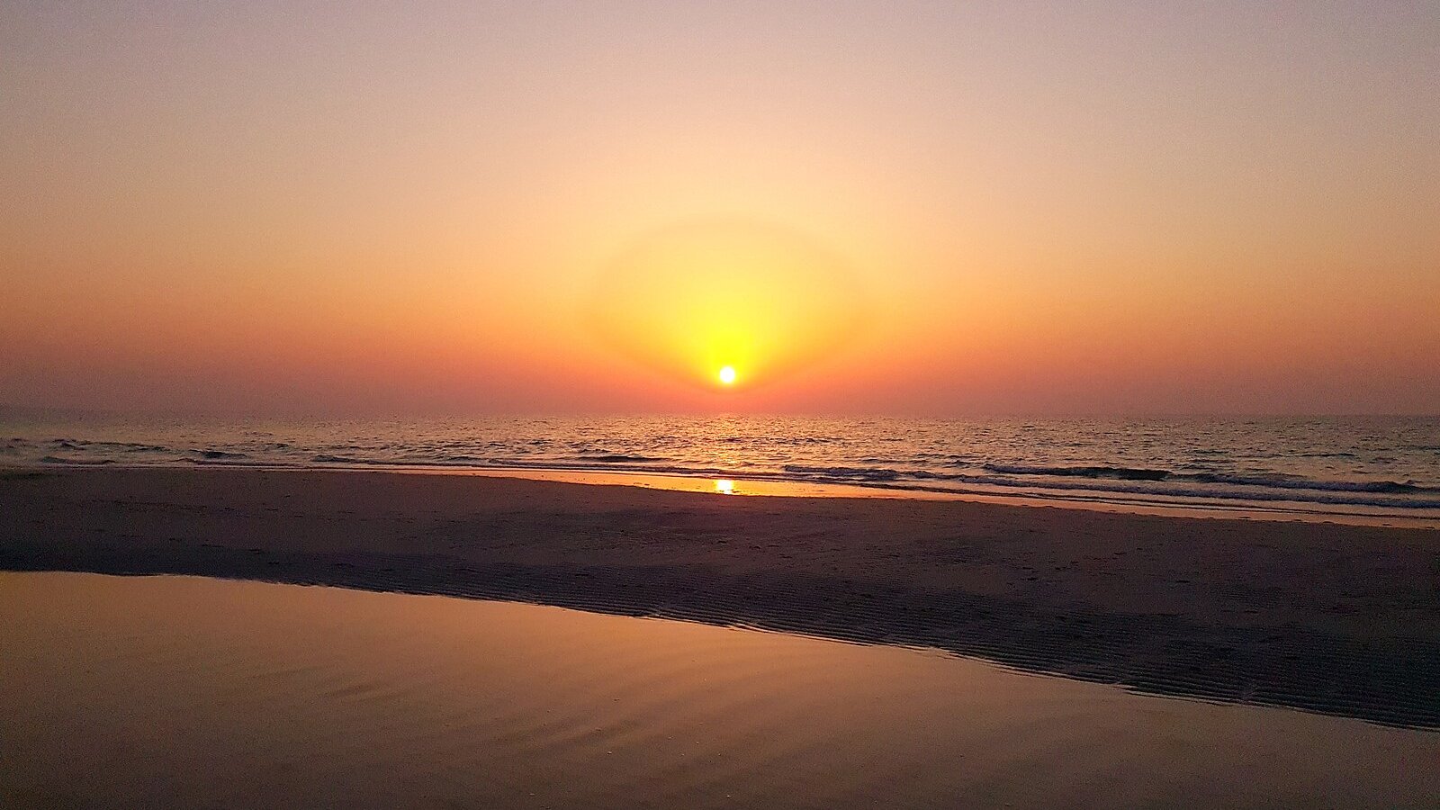 The sun setting over the Arabian Gulf, gilding the wet sand of Saadiyat Beach, Abu Dhabi