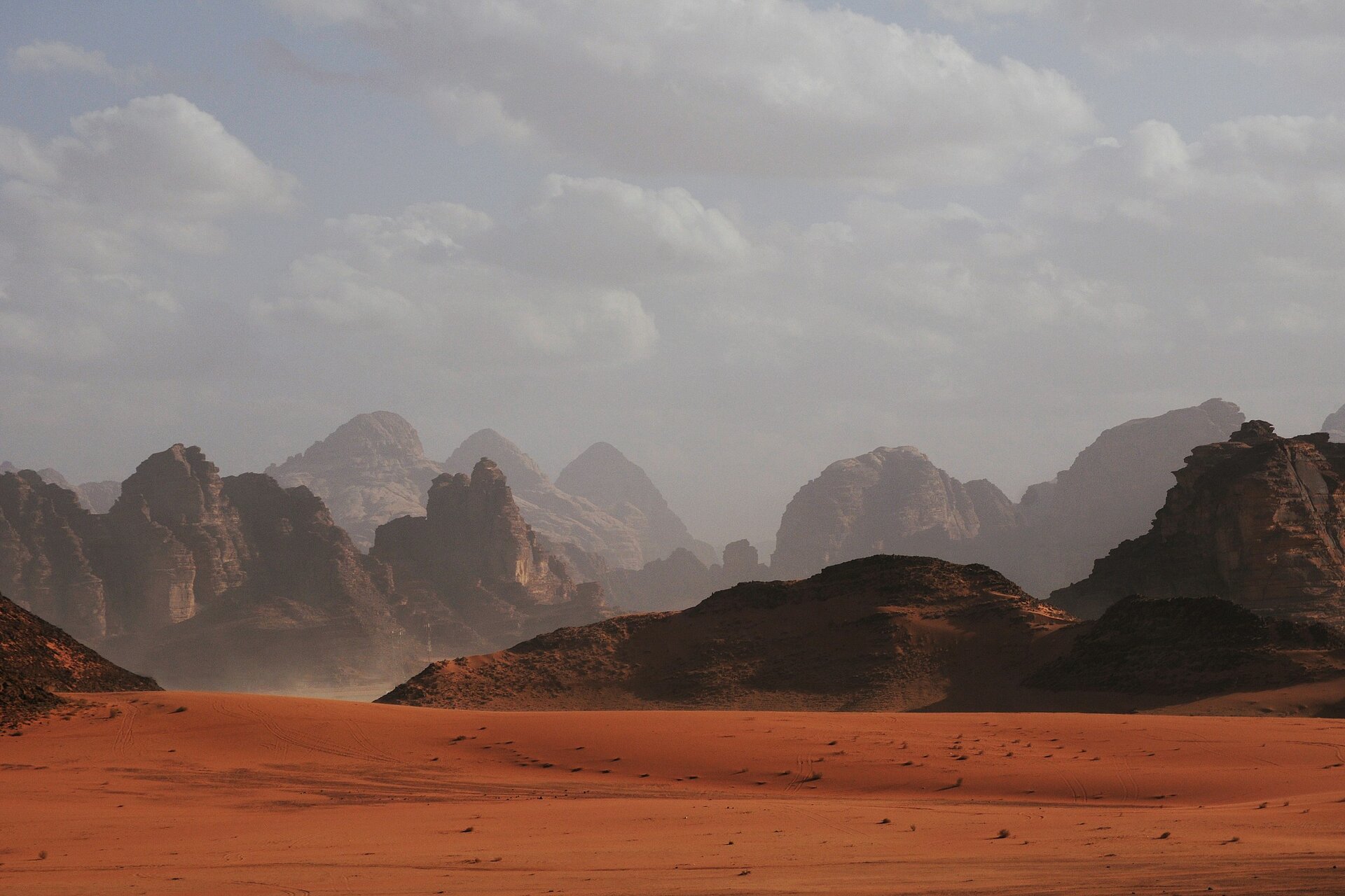 Red sand and sandstone mountains in the dusty light of Wadi Rum, Jordan