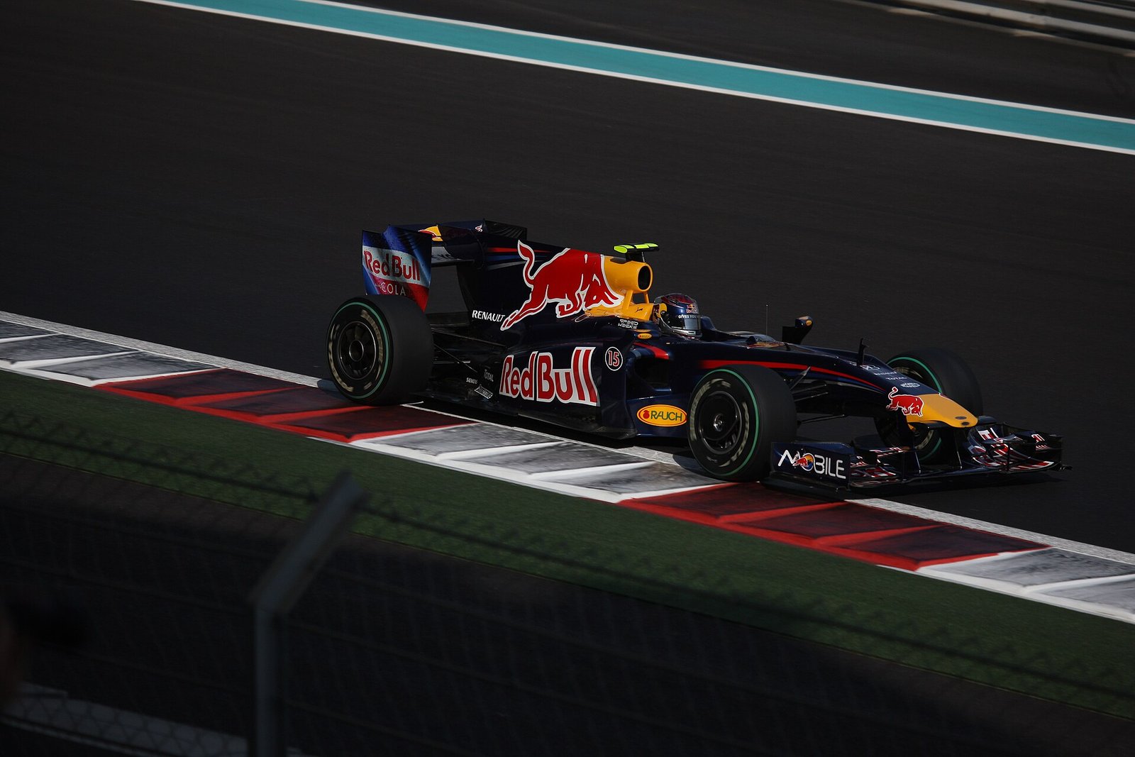 A Formula 1 car racing through the dusk light at the Yas Marina Circuit, Abu Dhabi.