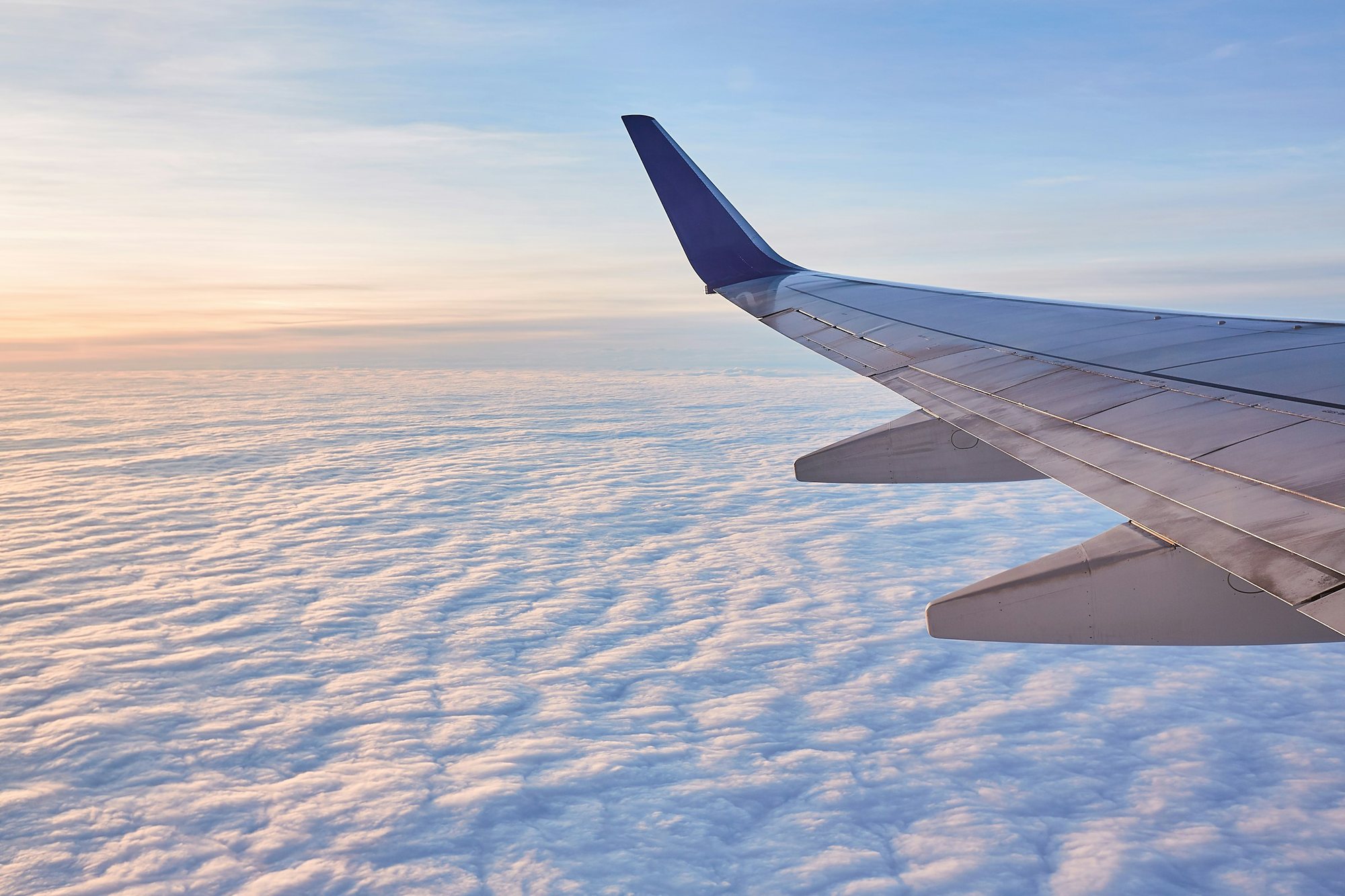 An airliner wing over a sea of morning cloud