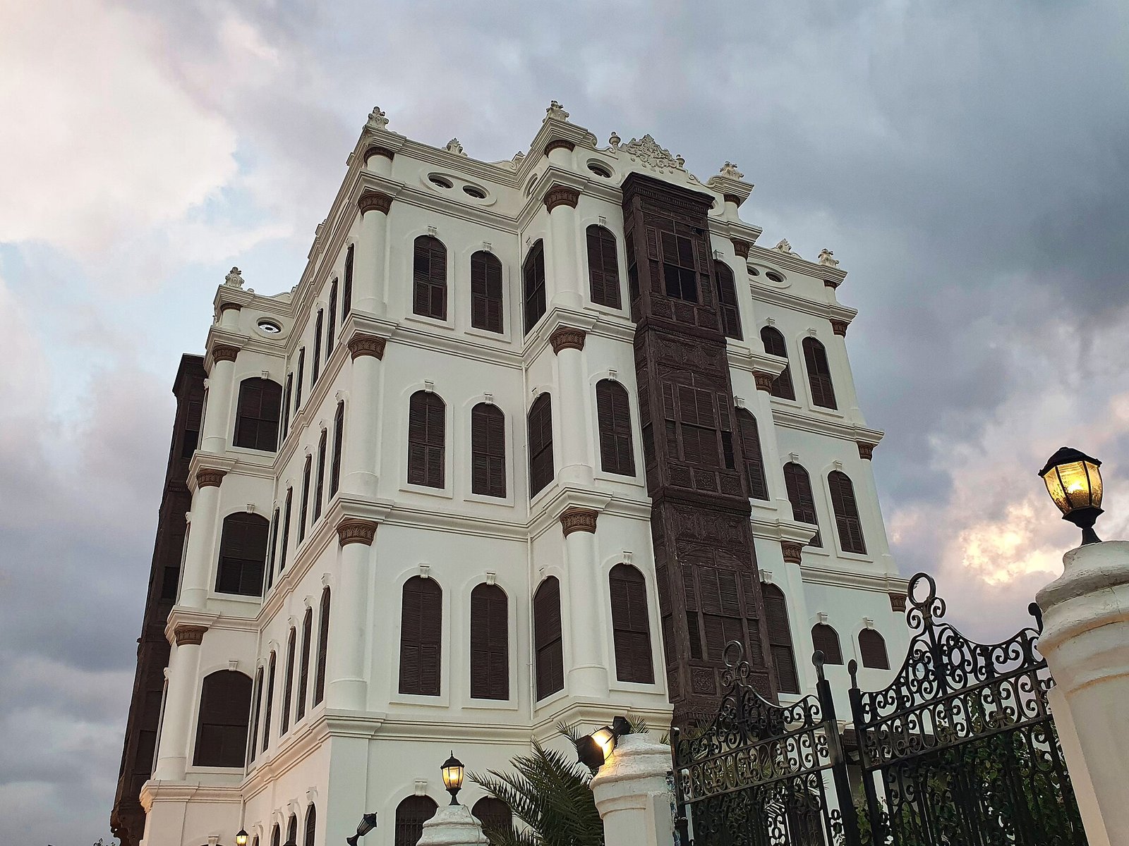 The white facade and carved wooden rawasheen of the 1905 Shubra Palace in Taif