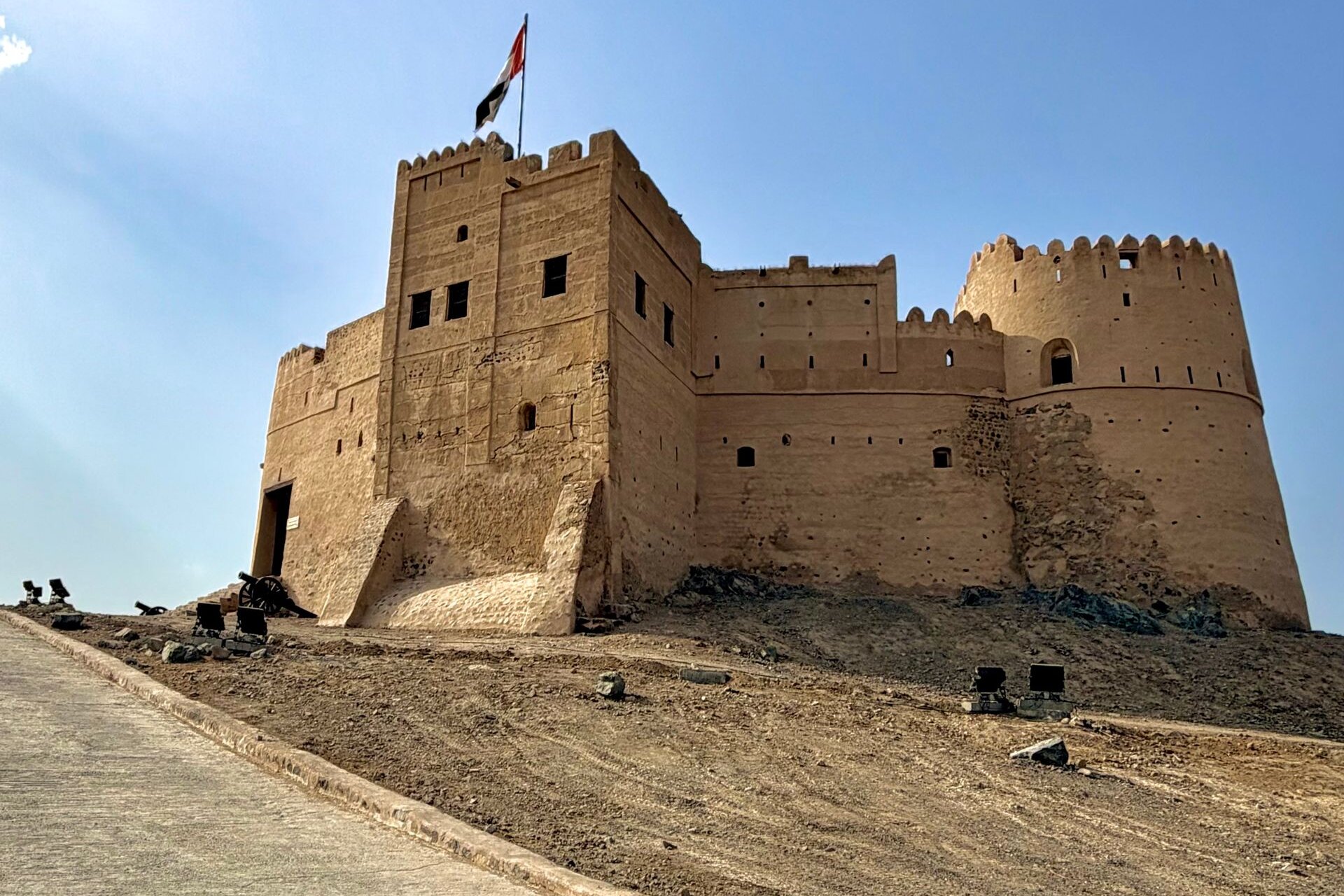 Fujairah Fort under a clear blue sky, the UAE flag flying above