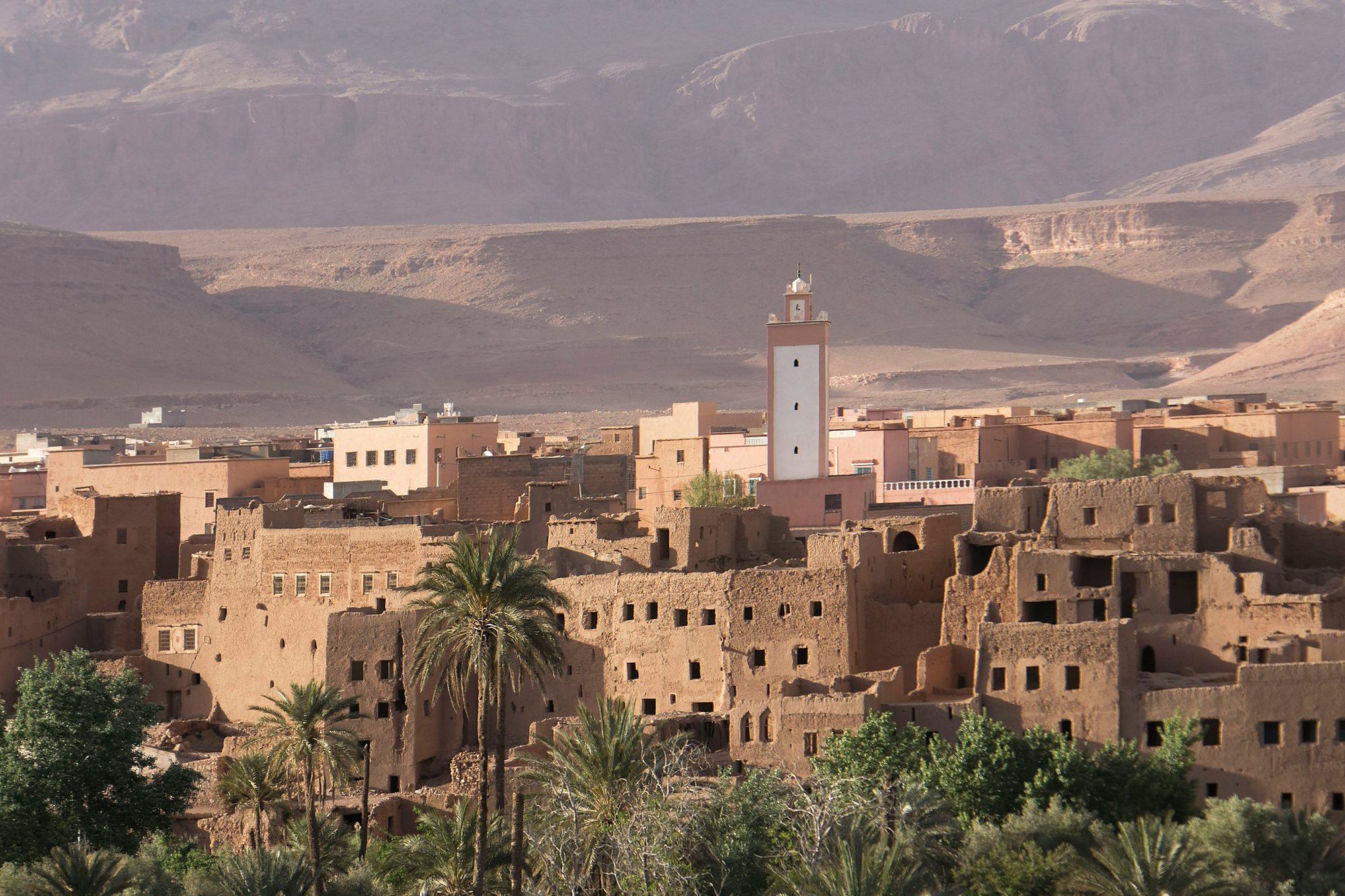 A kasbah village and minaret among palms below the mountains of southern Morocco