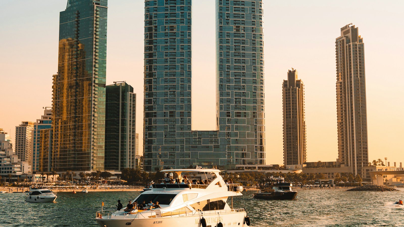 A motor yacht cruising past the towers of Dubai Marina at golden hour