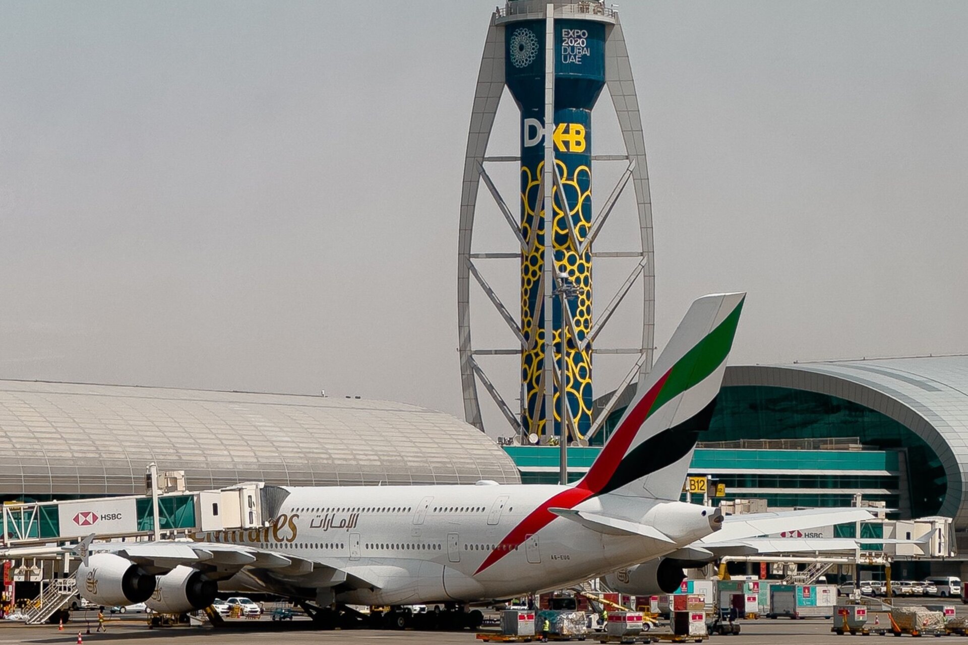 An Emirates A380 at the gate below the control tower of Dubai International Airport
