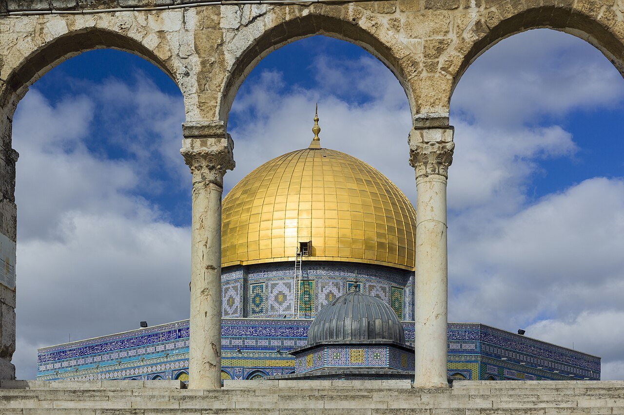 The golden Dome of the Rock in Jerusalem framed by the stone arches of a qanatir on the Temple Mount.