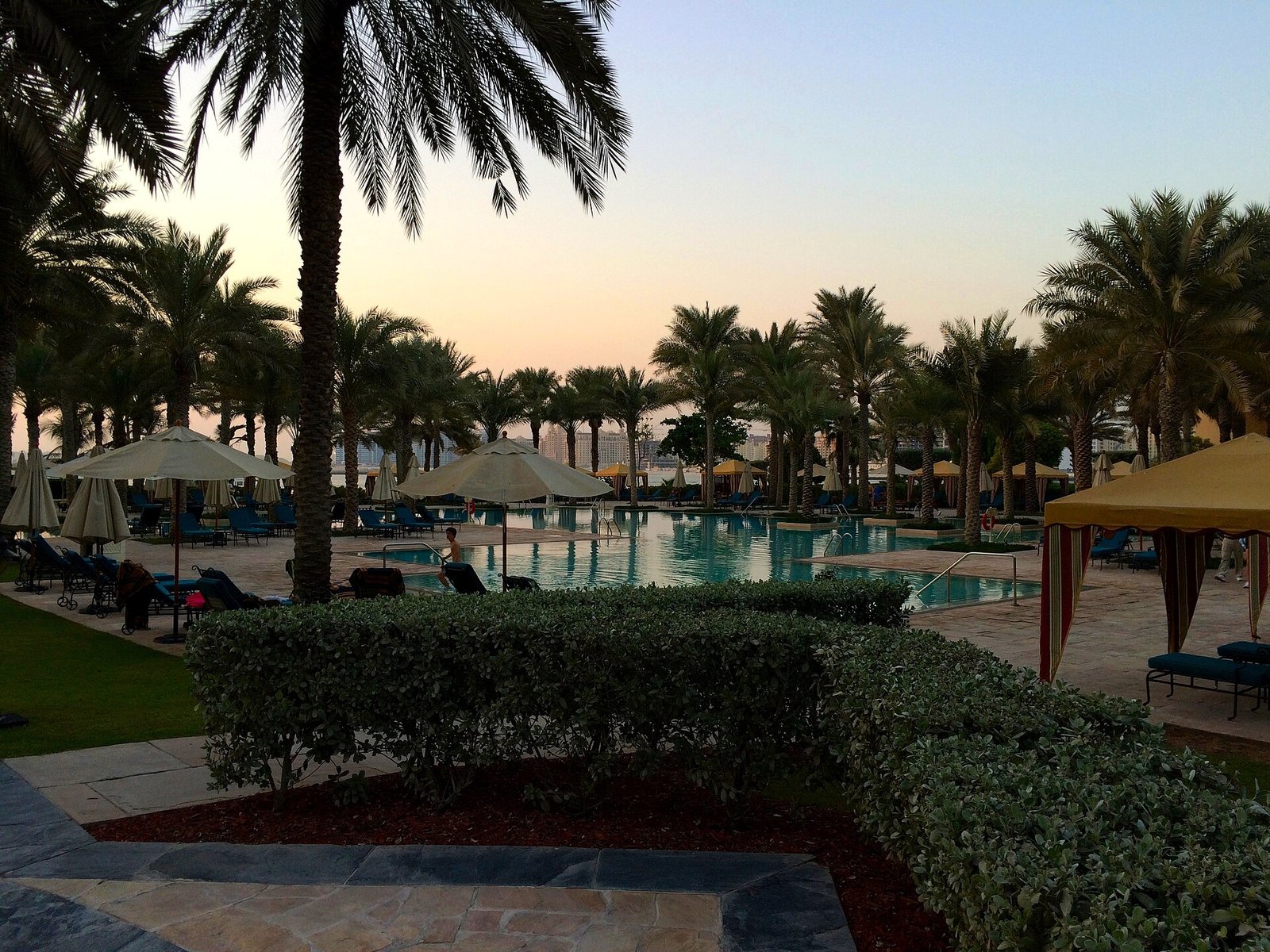Palms, cabanas and a quiet pool at dusk in the gardens of the One&Only Royal Mirage, Dubai.