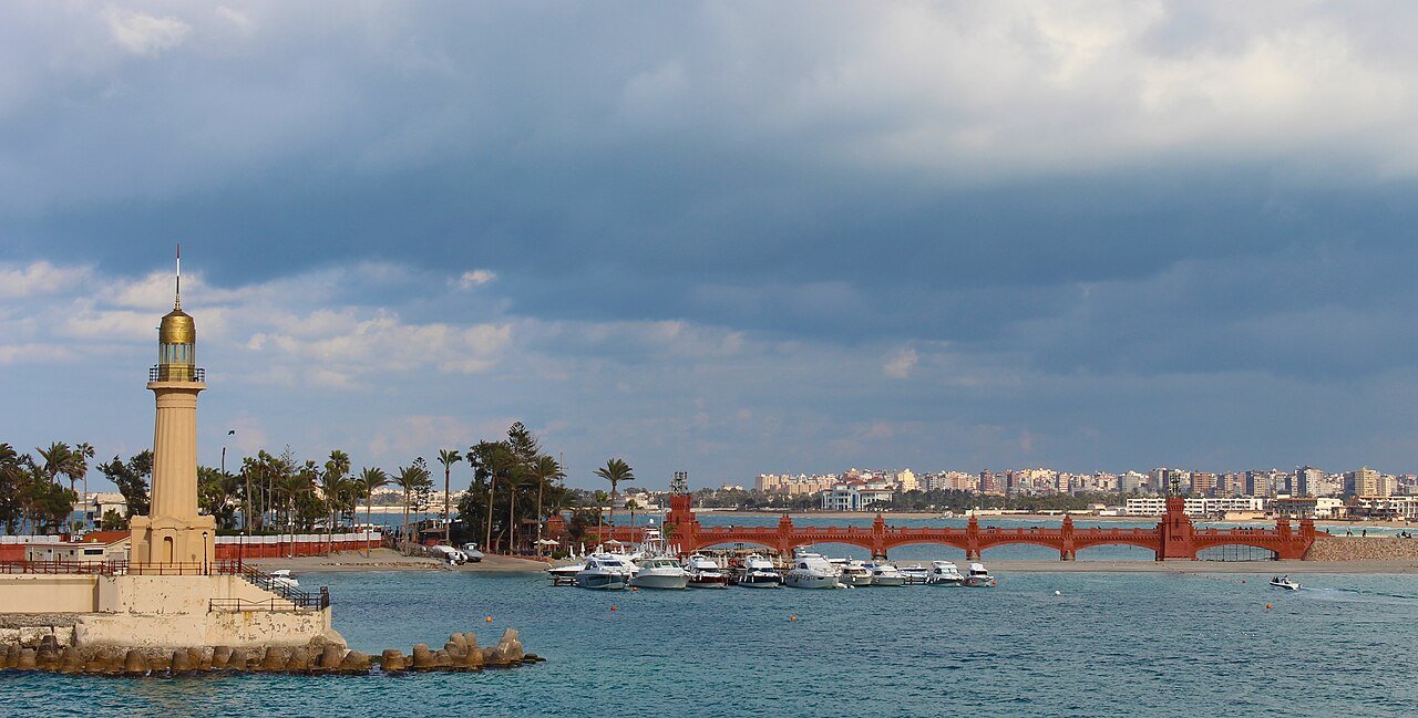 The lighthouse and arched bridge at Montaza on the Alexandria seafront, boats moored in the bay.