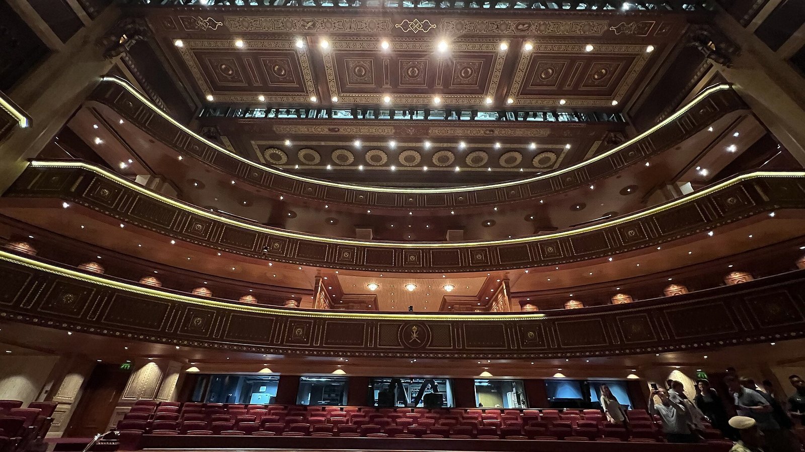 The tiered wooden balconies and gilded ceiling of the auditorium at the Royal Opera House Muscat