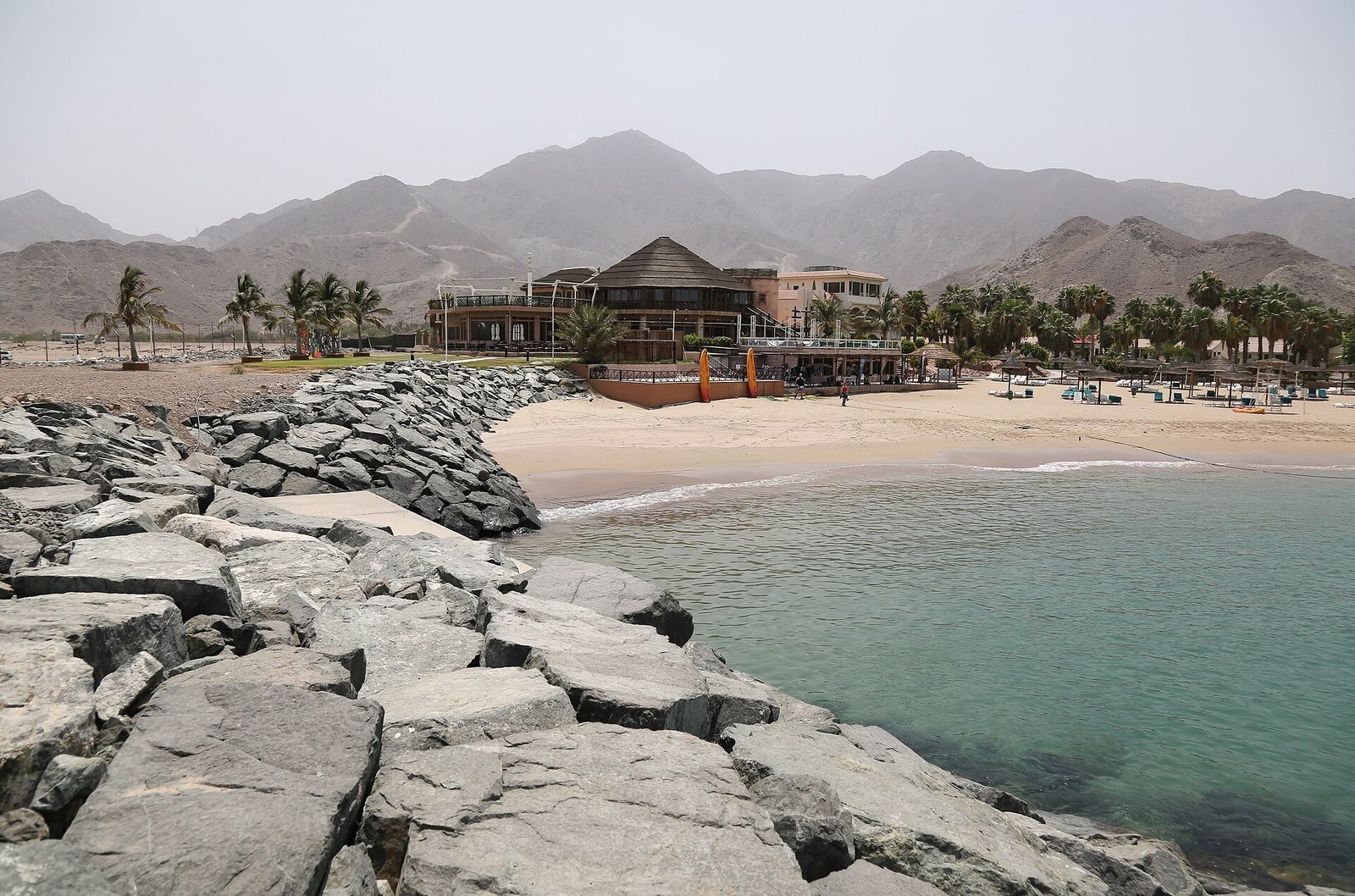 A sheltered sandy cove and palm-lined resort below the rugged Hajar Mountains on Fujairah's Gulf of Oman coast.