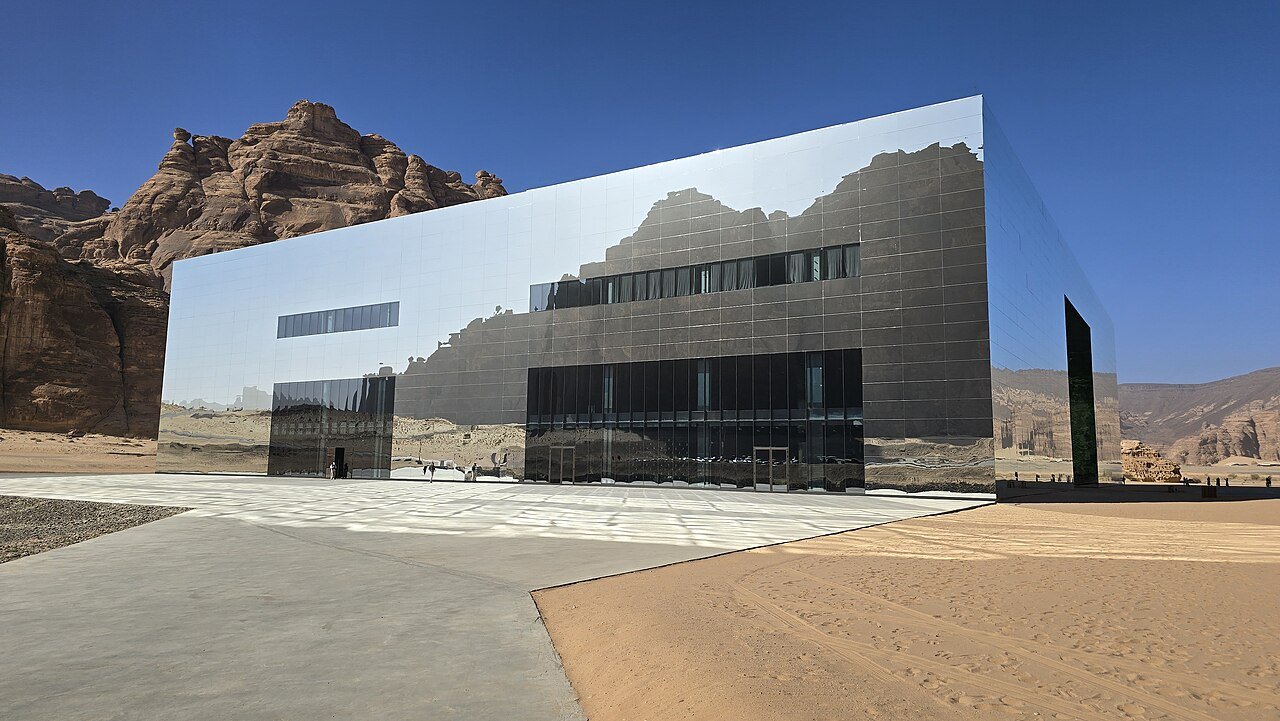 The mirrored facade of Maraya concert hall reflecting the sandstone cliffs of AlUla's Ashar Valley.