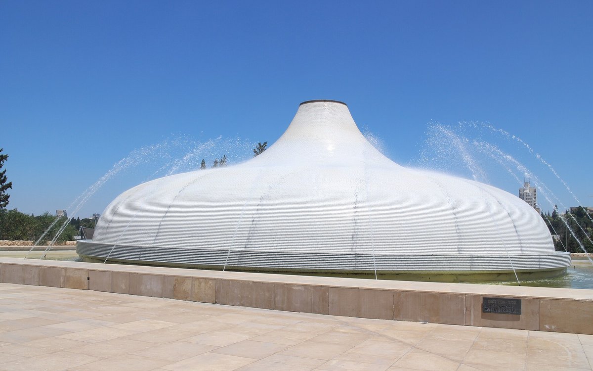 Fountains arc over the white, lid-shaped dome of the Shrine of the Book at the Israel Museum in Jerusalem.