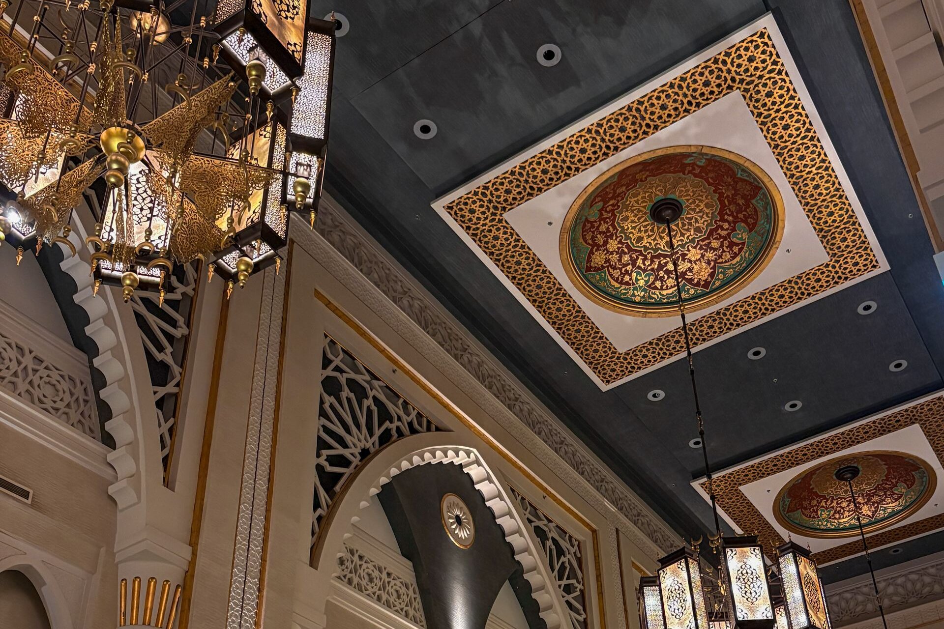 Gilded lanterns and carved arches in a palace-style hall