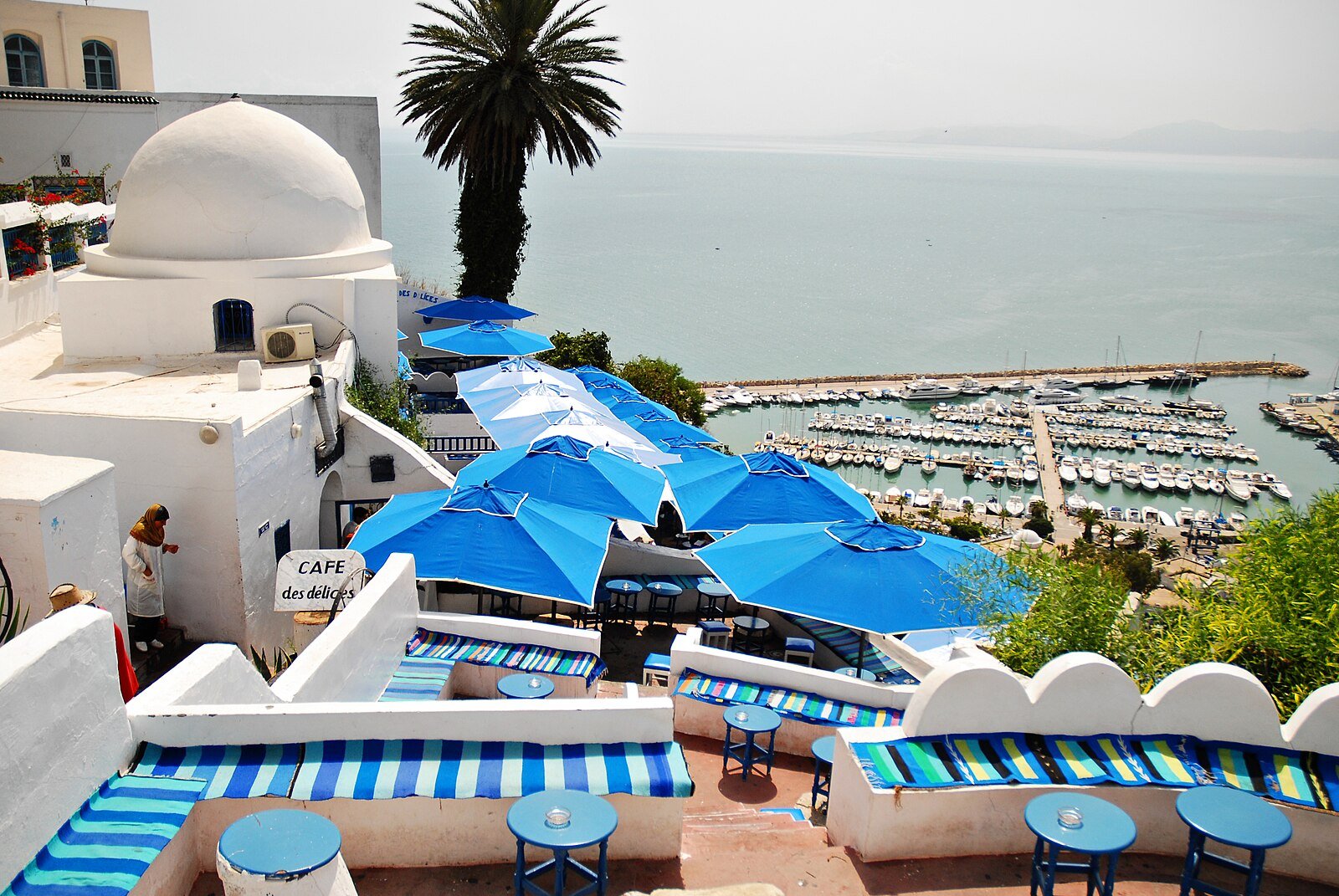 Blue parasols on the terraces of a whitewashed cafe above the marina of Sidi Bou Said and the Gulf of Tunis.